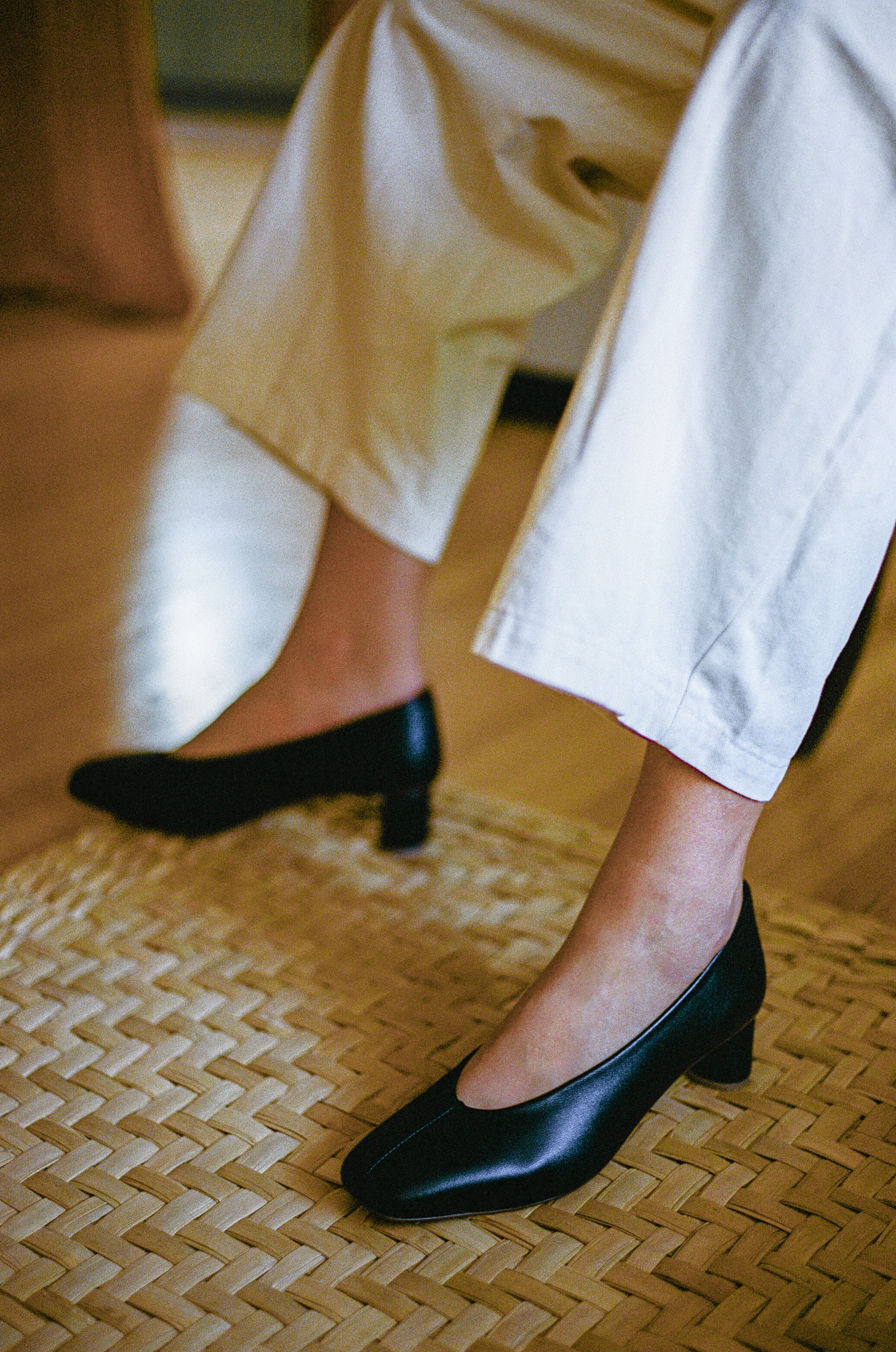 Model wears black leather pump with sculptural oval heel and center seam.