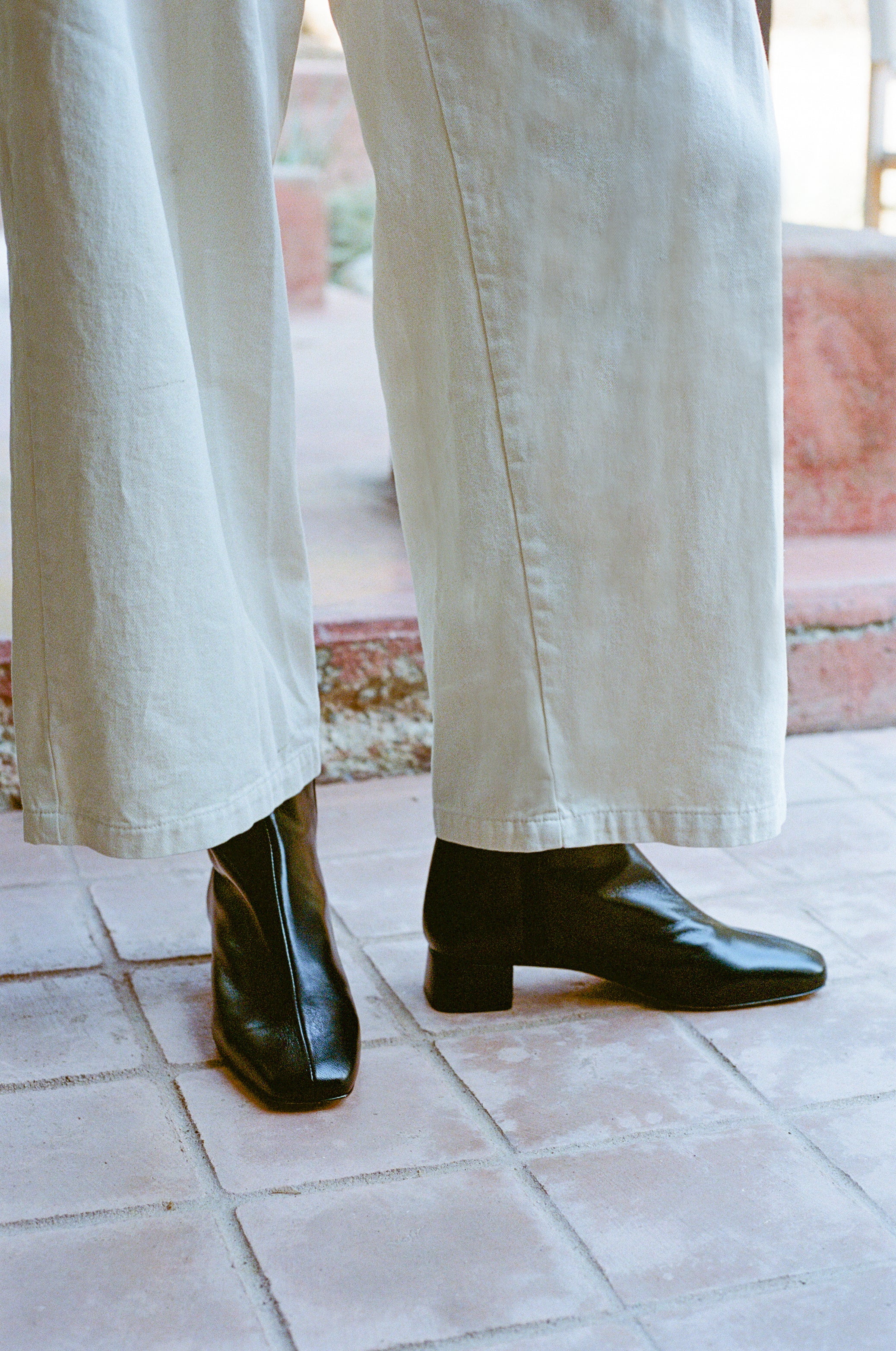 Model wears black ankle boot with center seam and side zipper.