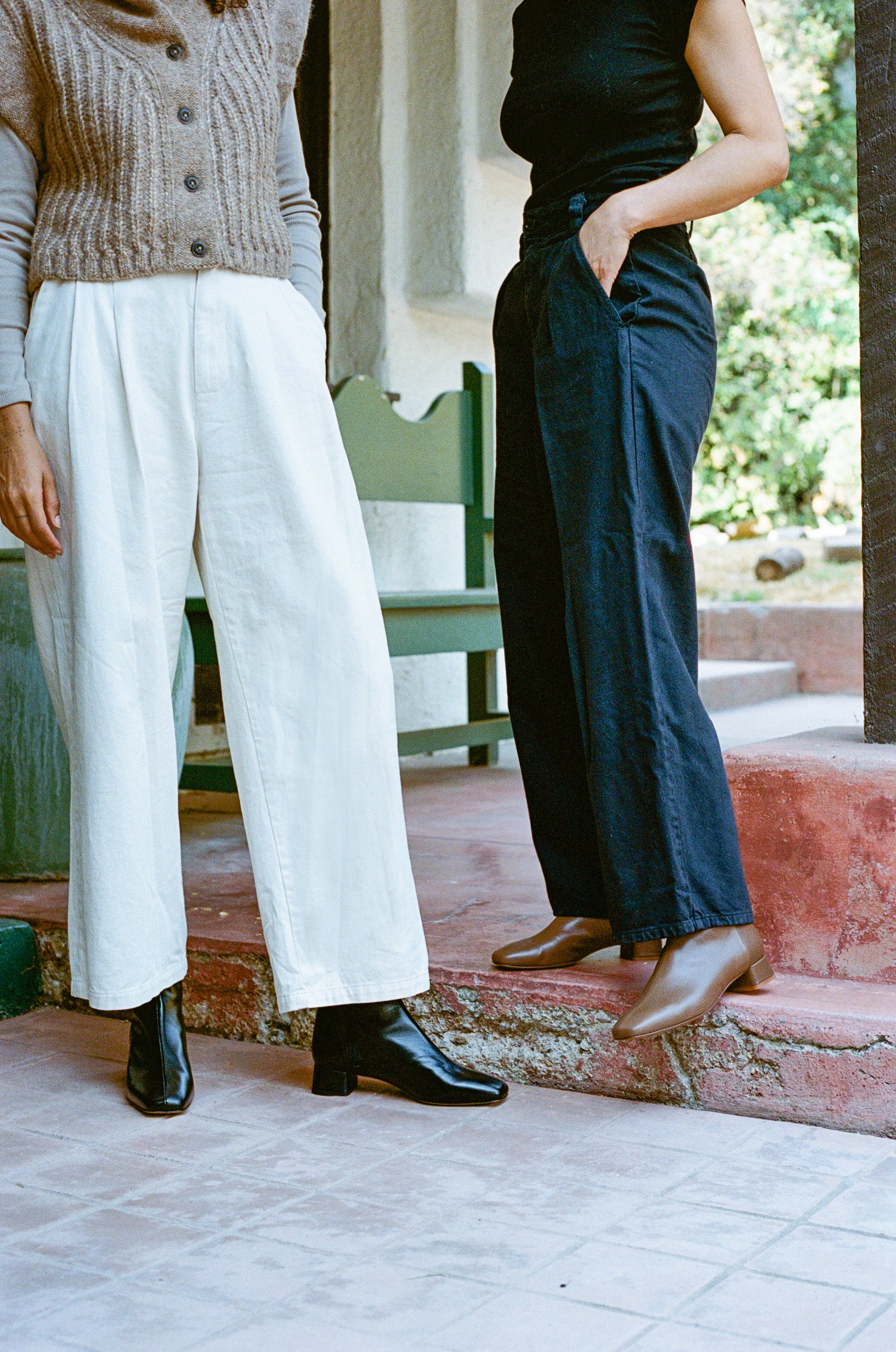 Model wears black ankle boot with center seam and side zipper.