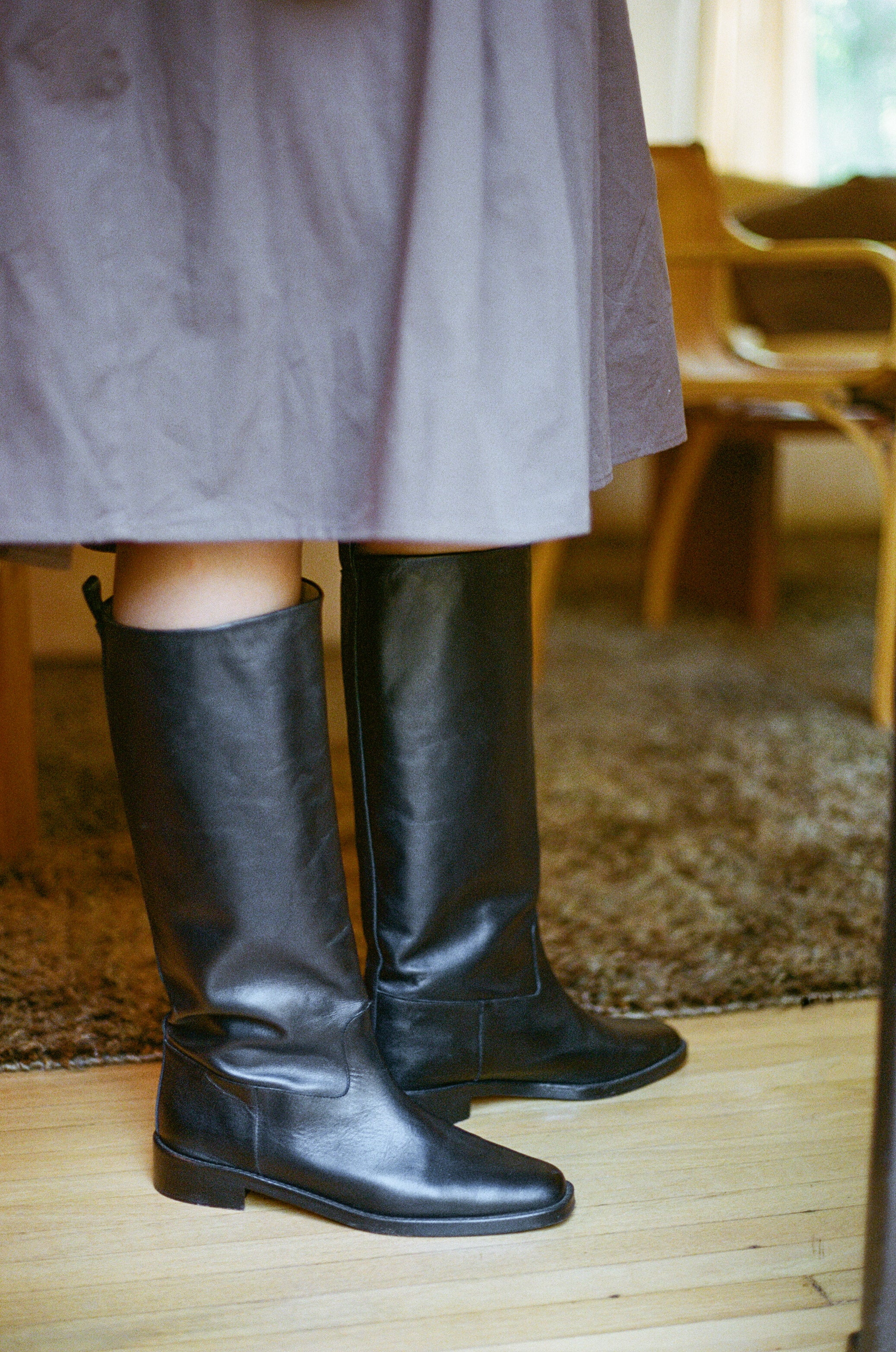 Model wears tall black riding boot with almond shaped toe.