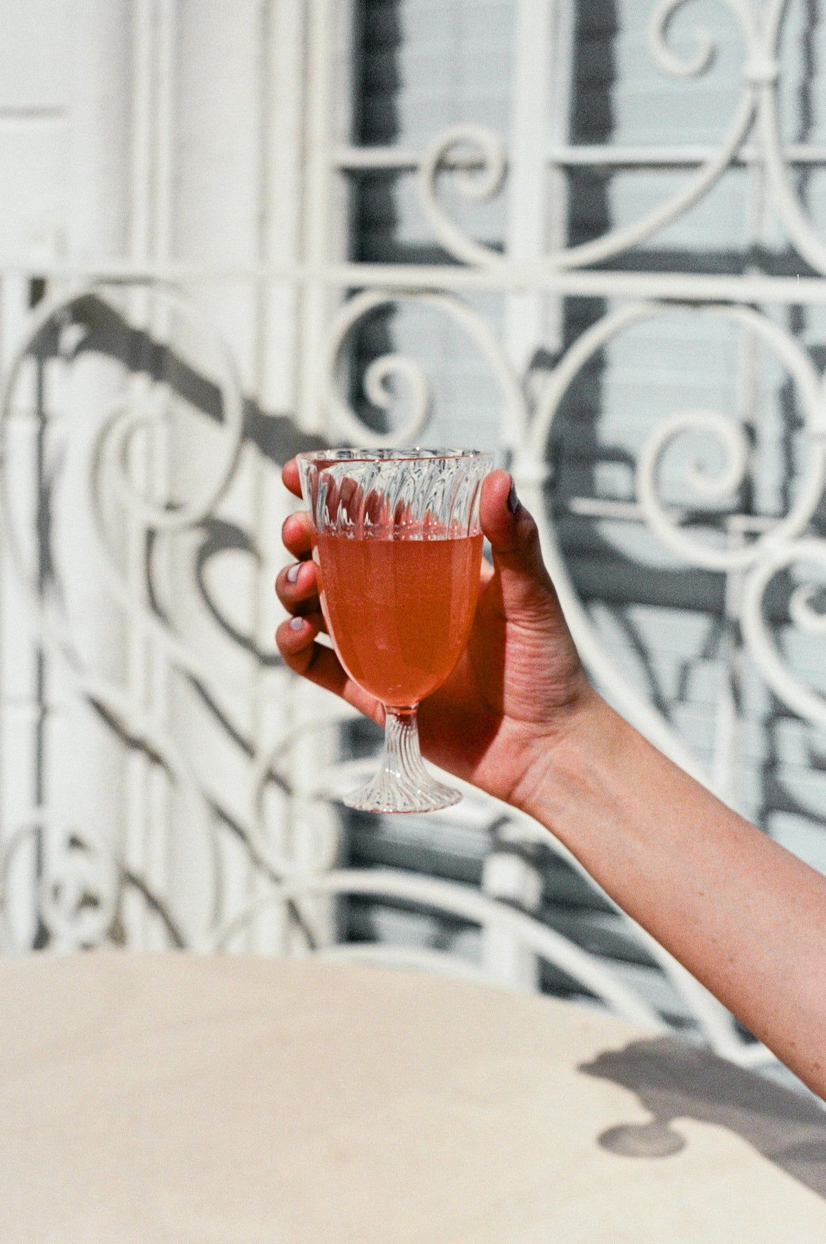 Model holds ribbed wine glass filled with orange wine.