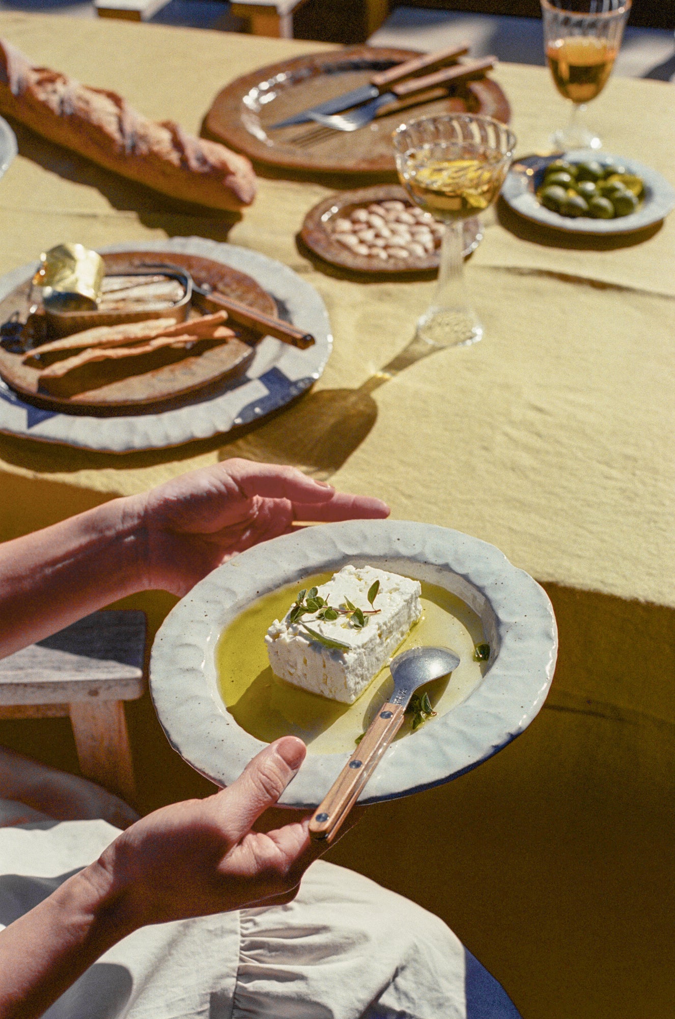 Model holds handmade ceramic plate with white glaze over tablescape.