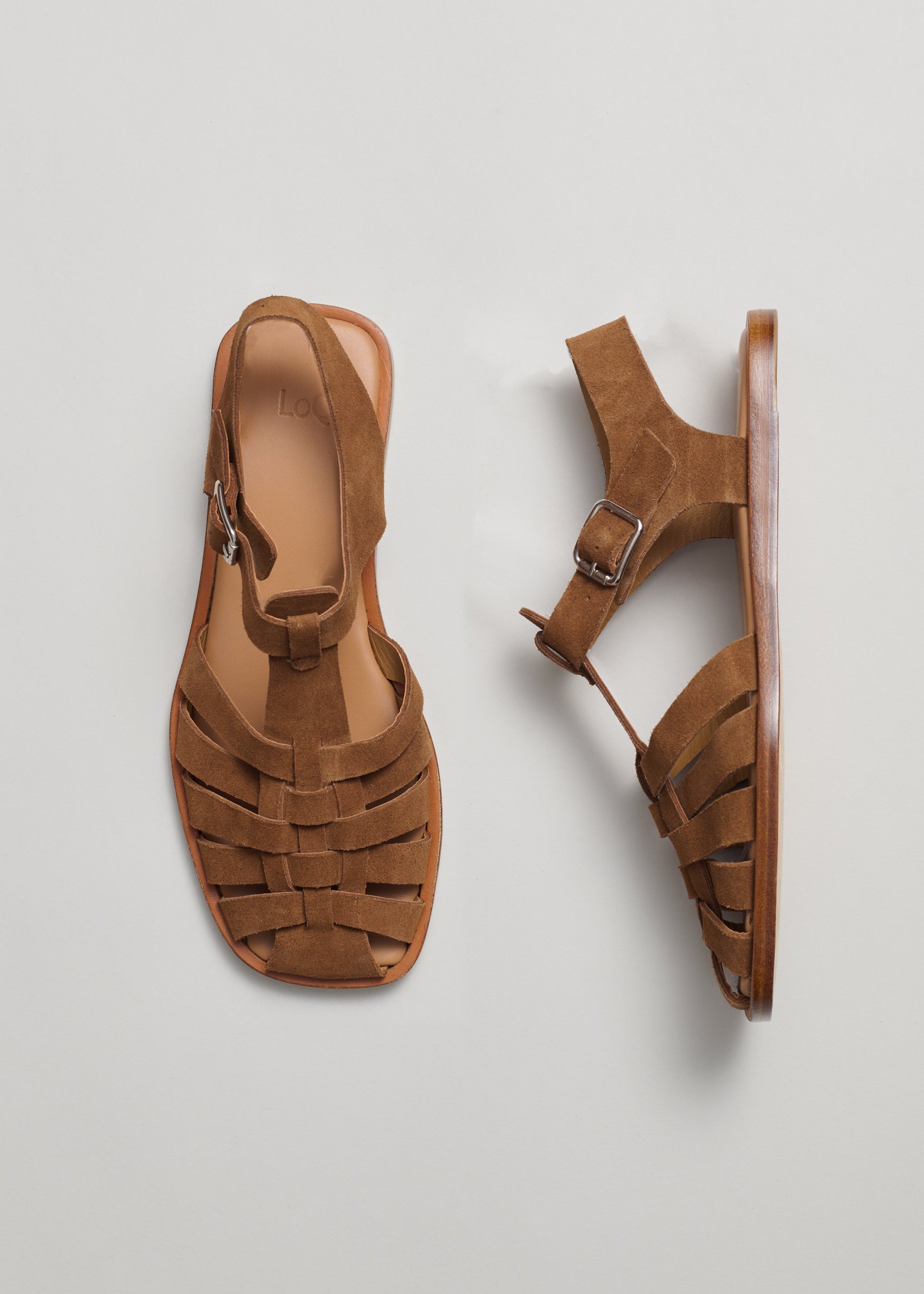 Pair of brown suede fisherman sandals on a light gray background