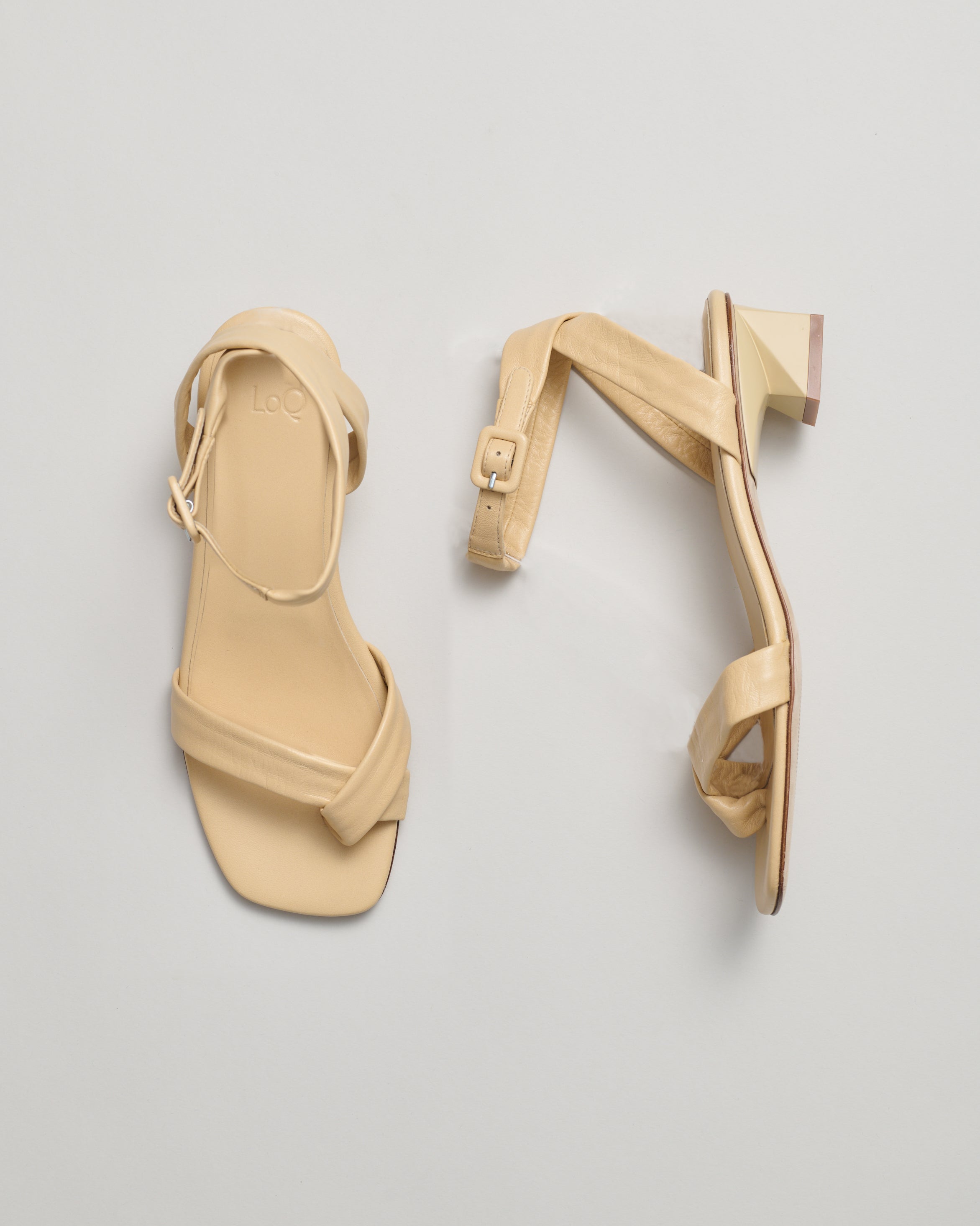 Beige high-heeled sandals on a light gray background