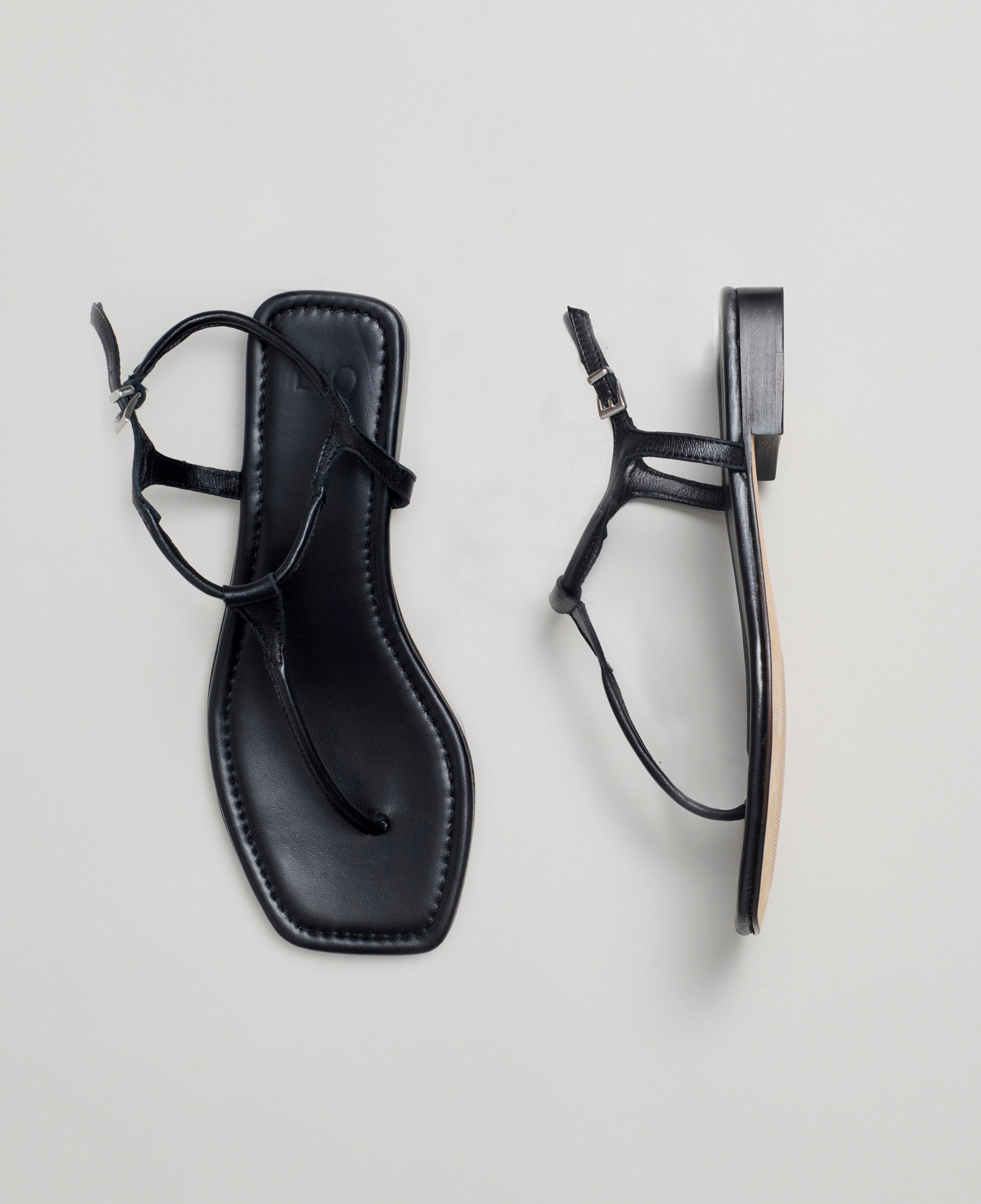 Black sandal with a strap on a light gray background