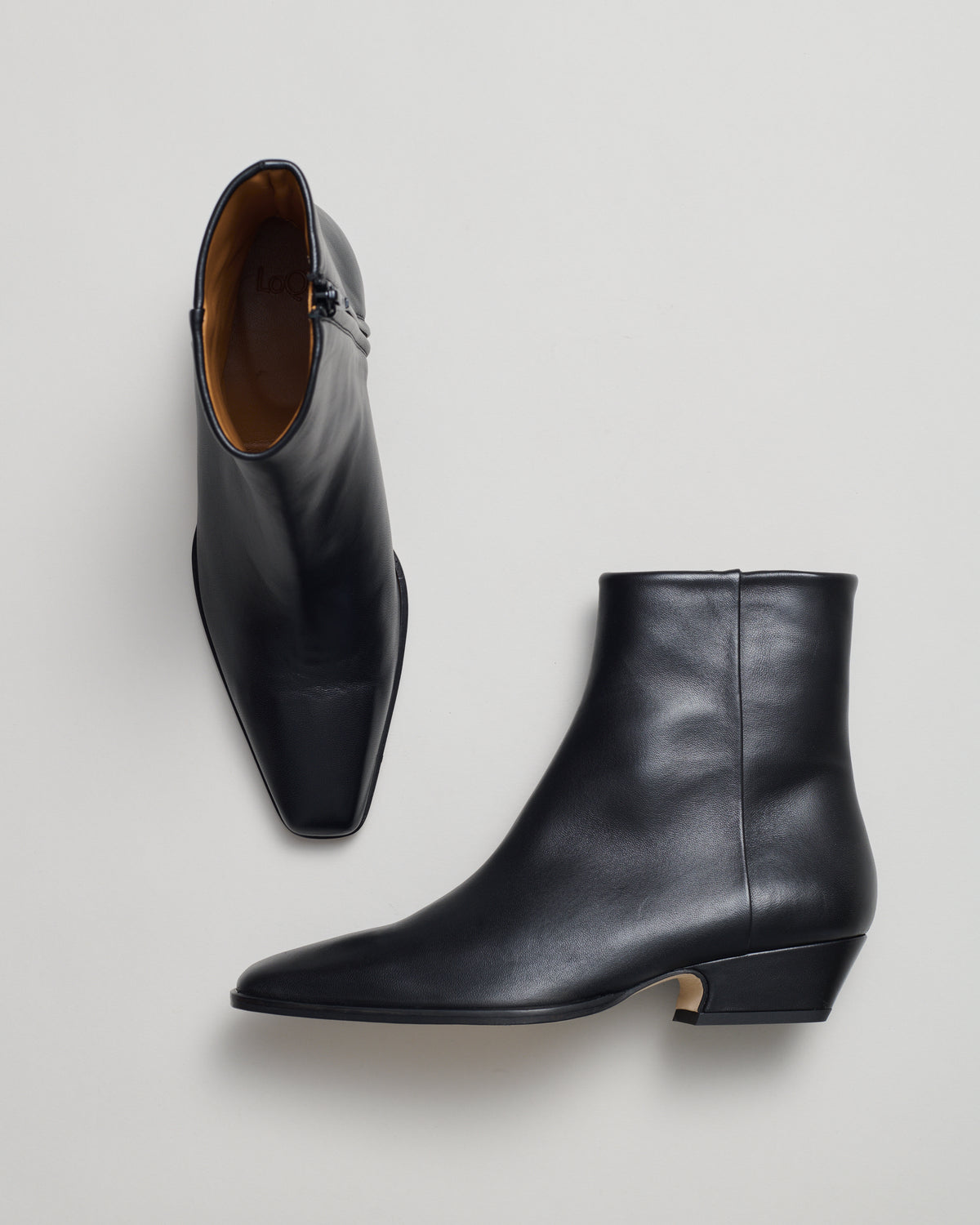 A pair of black leather western style ankle boots with pointed toes and low cuban heel.