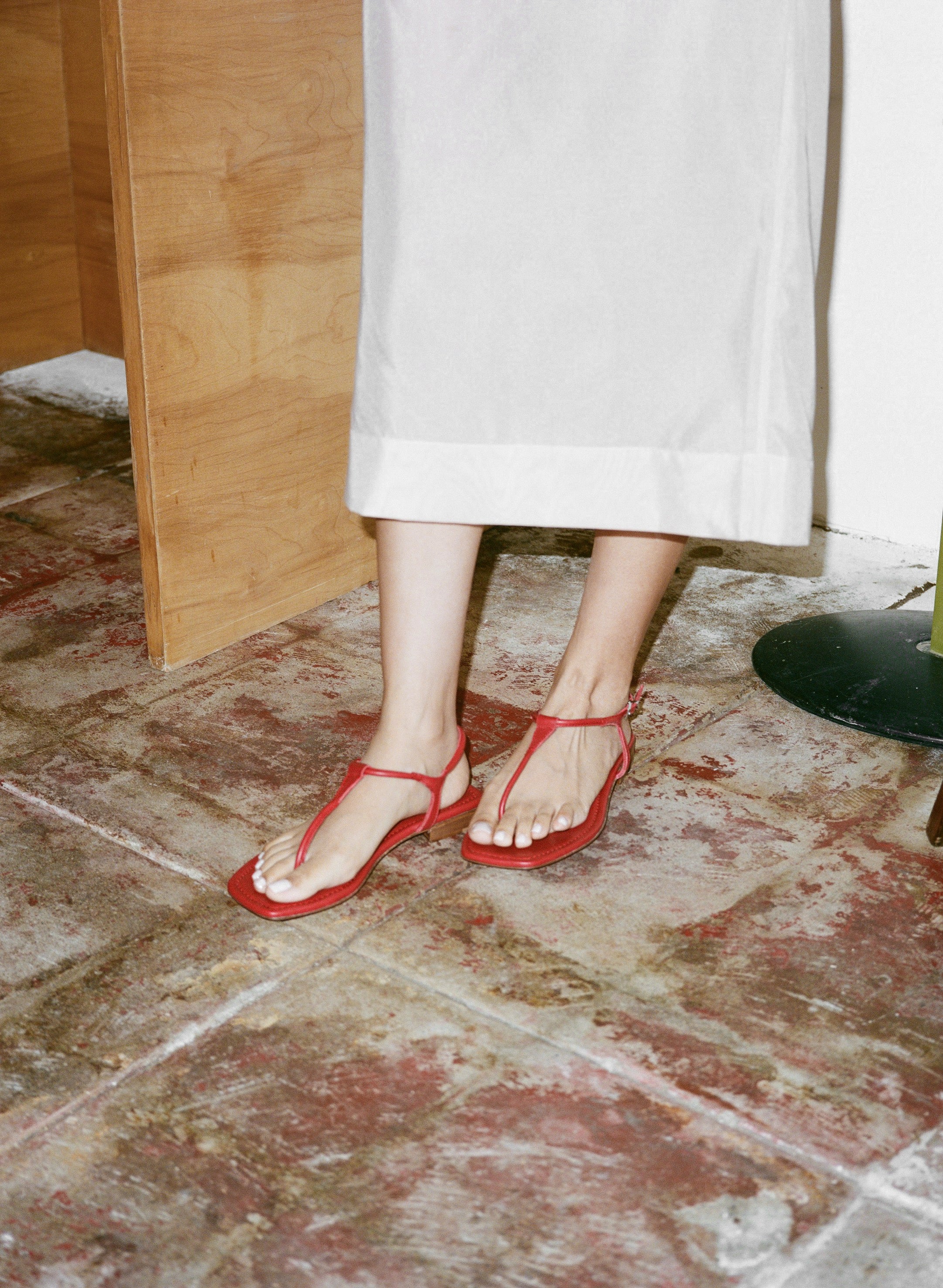 Person wearing red sandals on a concrete floor