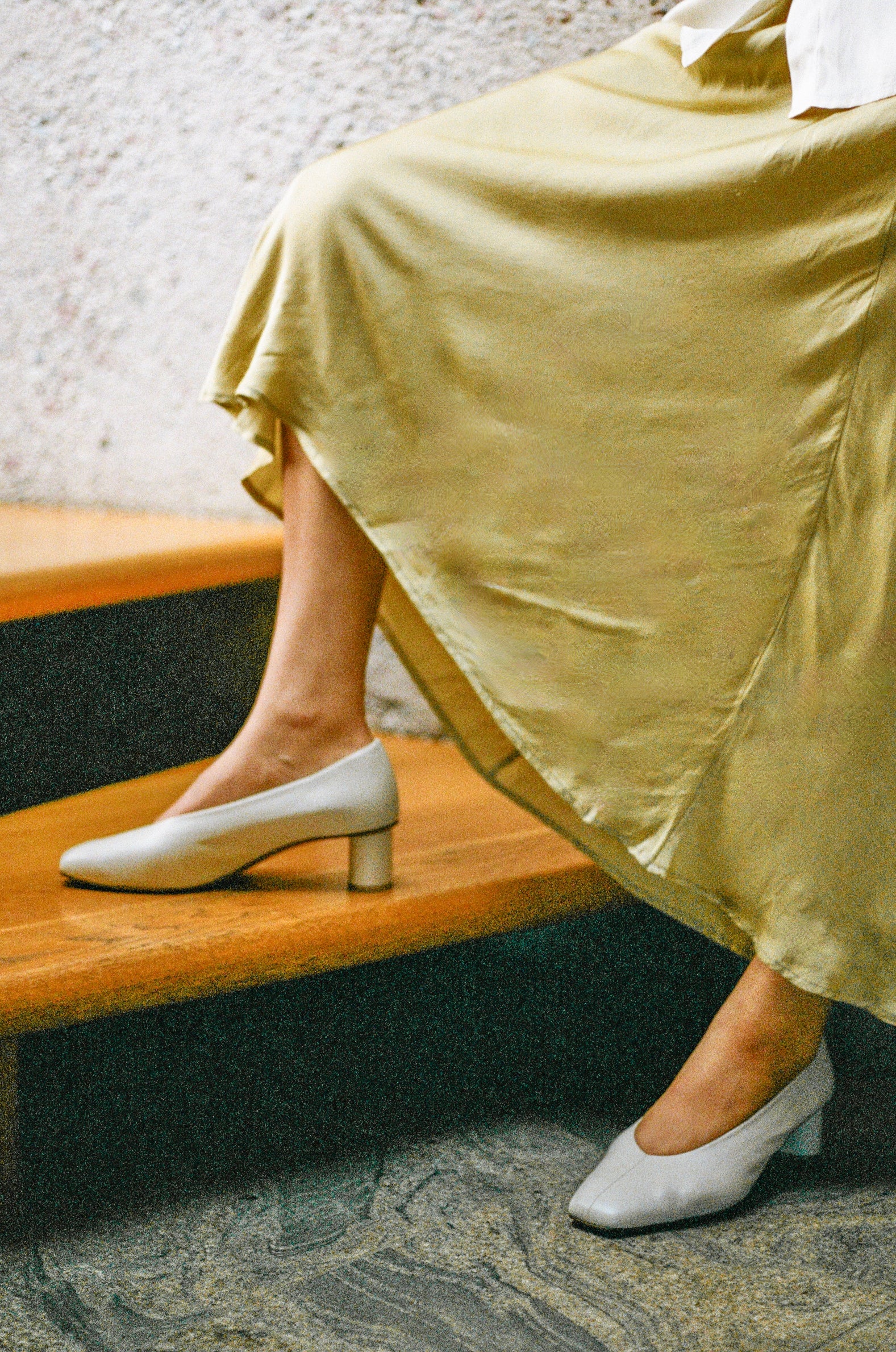 Model wears off white leather pump with center seam and oval shaped heel.