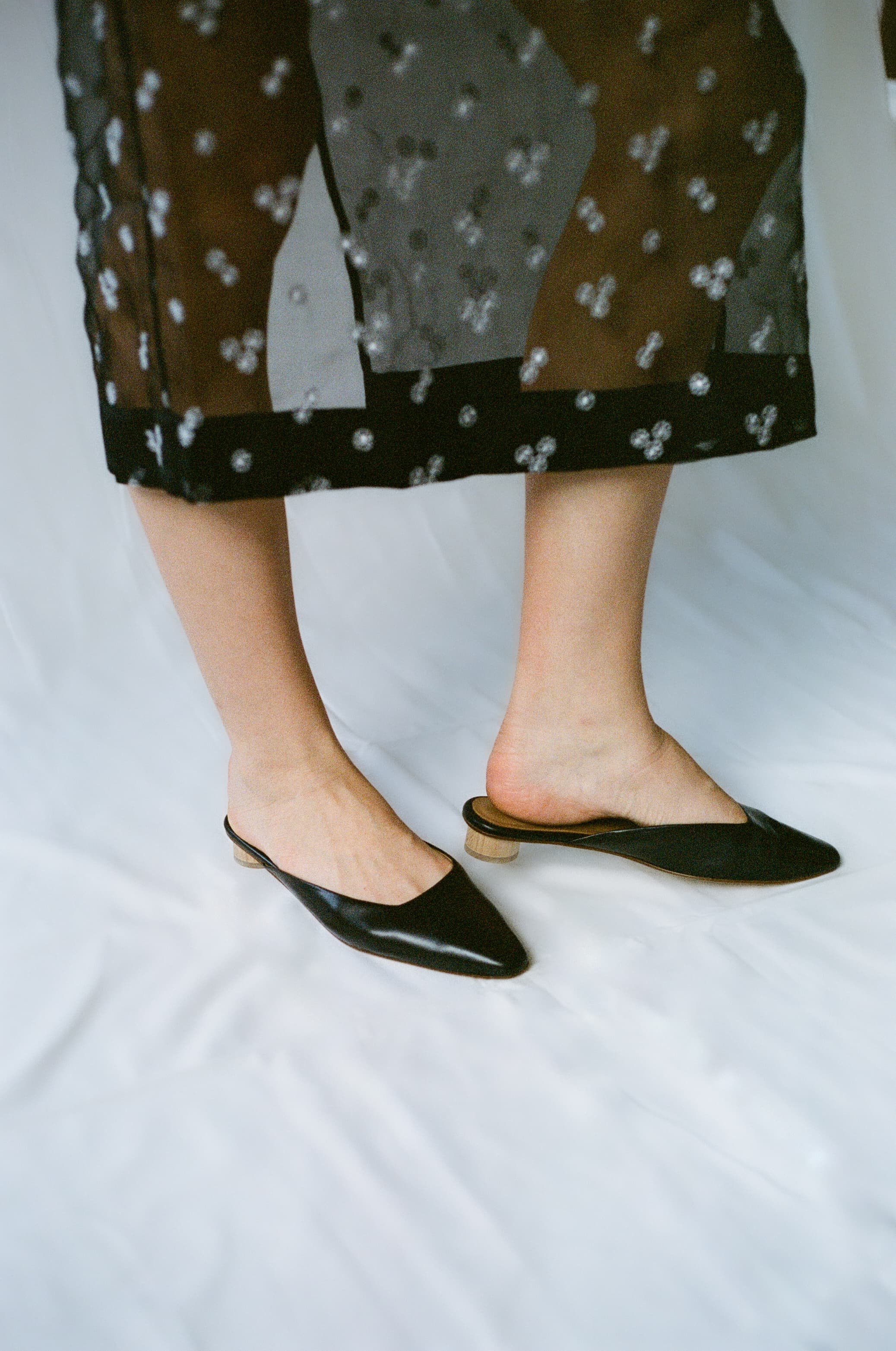 Person wearing black flat shoes and sheer skirt on a white background