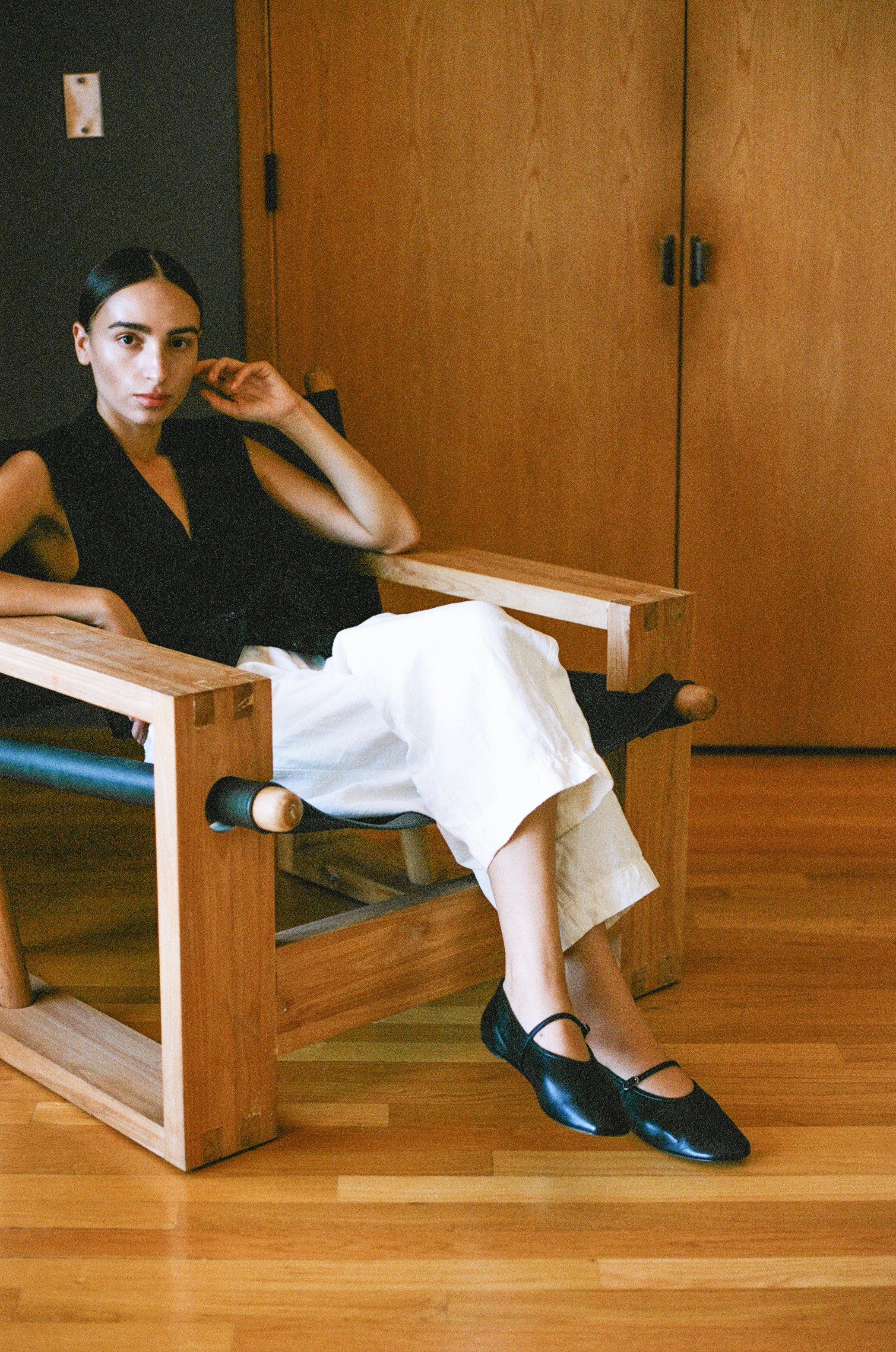 Model wears black leather mary jane style flat shoe with strap and buckle closure.