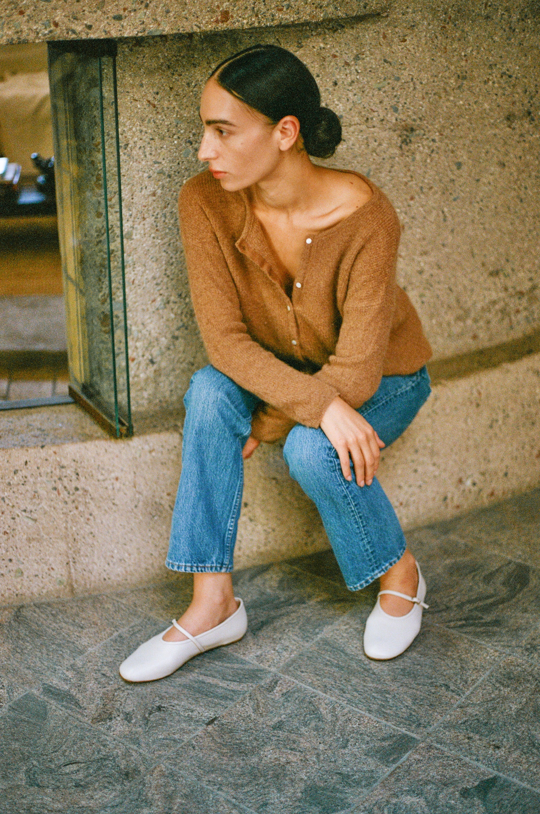 Model wears off white colored leather mary jane style flat shoe with strap and buckle closure.