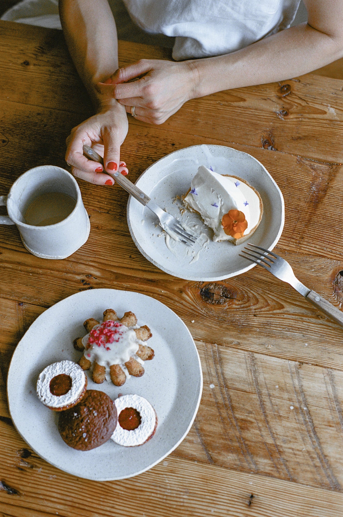 Model poses with white ceramic plates with pastries and mug.