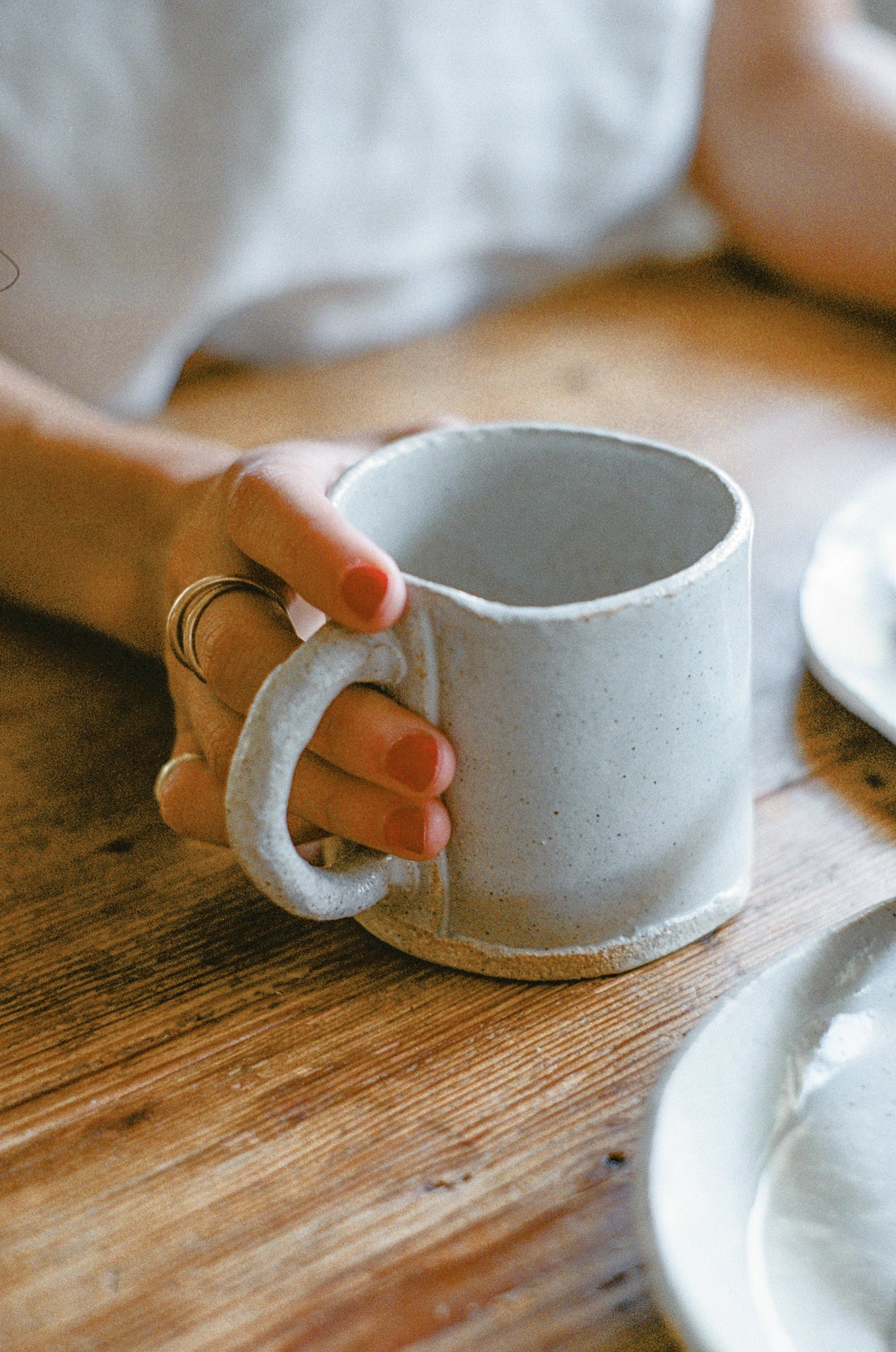 Model holds white ceramic mug.