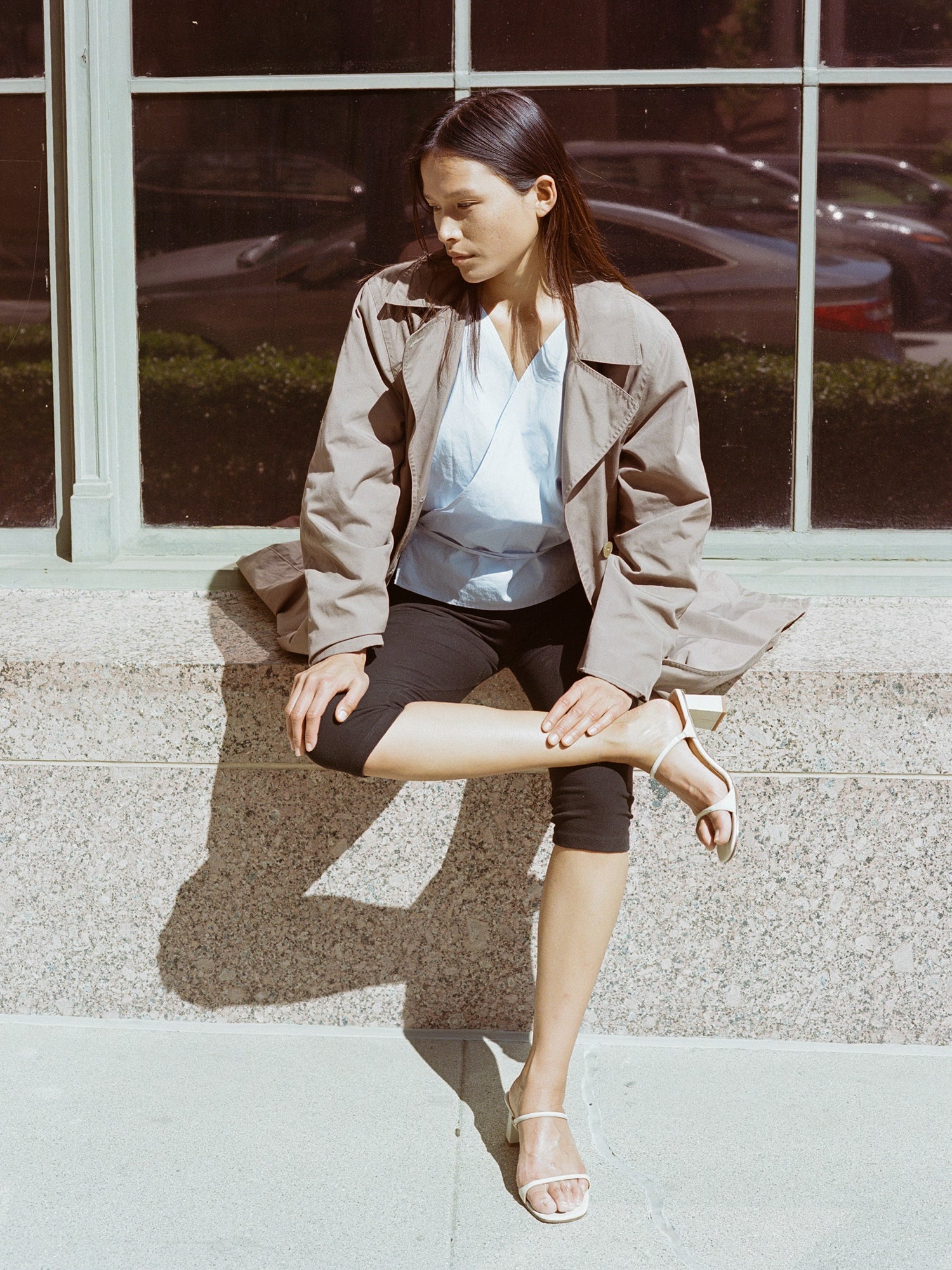 Model wears off white heeled leather sandal featuring two thin straps and square block heel.
