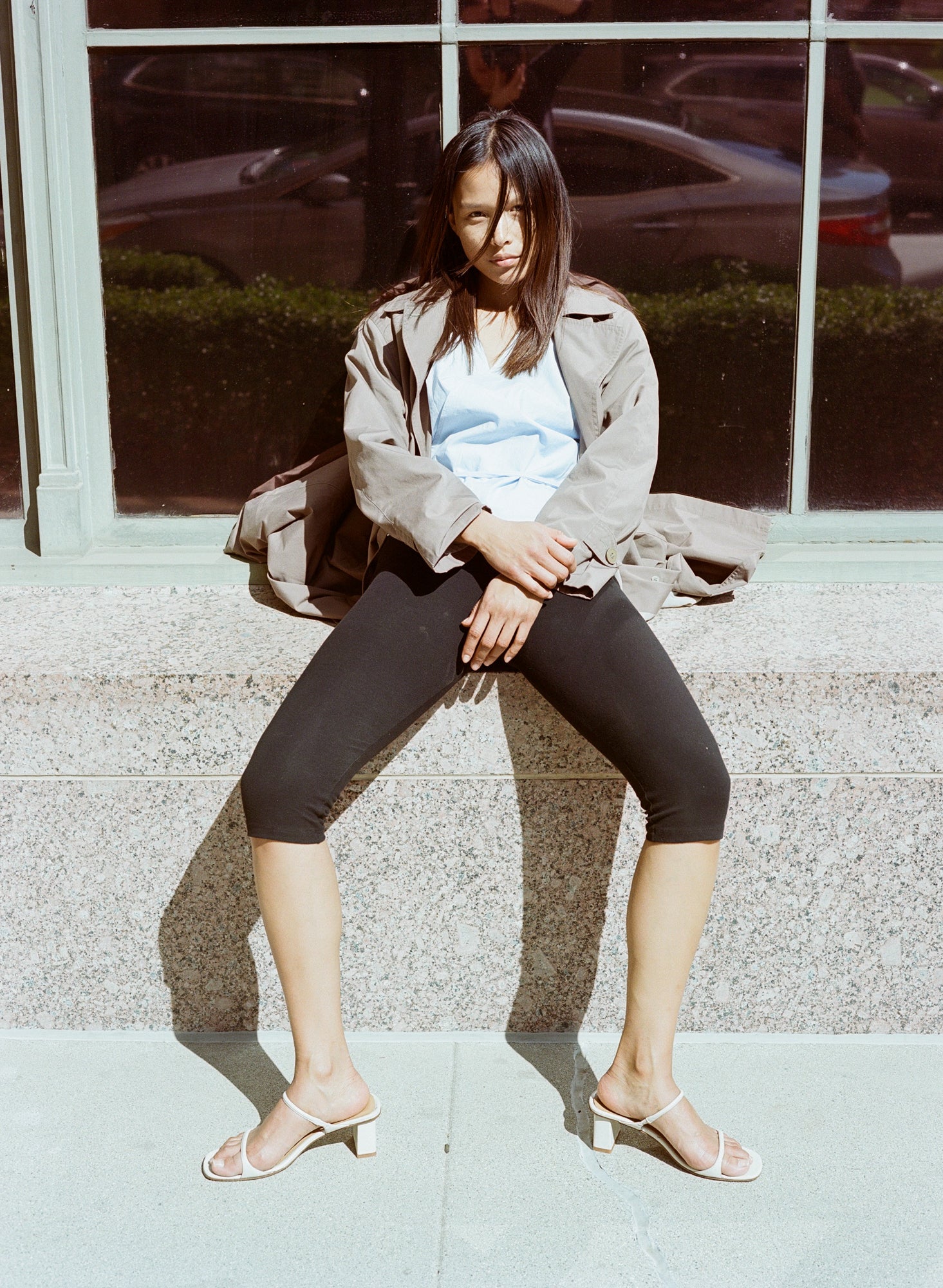 Model wears off white heeled leather sandal featuring two thin straps and square block heel.