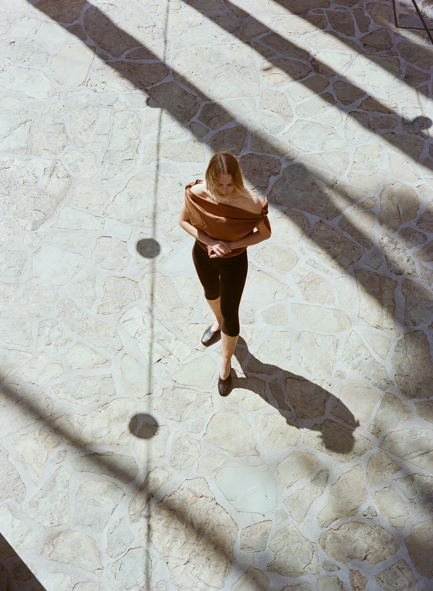 Model wears flat black leather slides with v shaped upper and center seam.