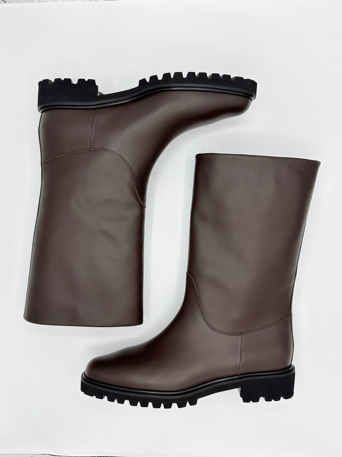 A pair of mid-calf brown leather boots with chunky black lug soles.
