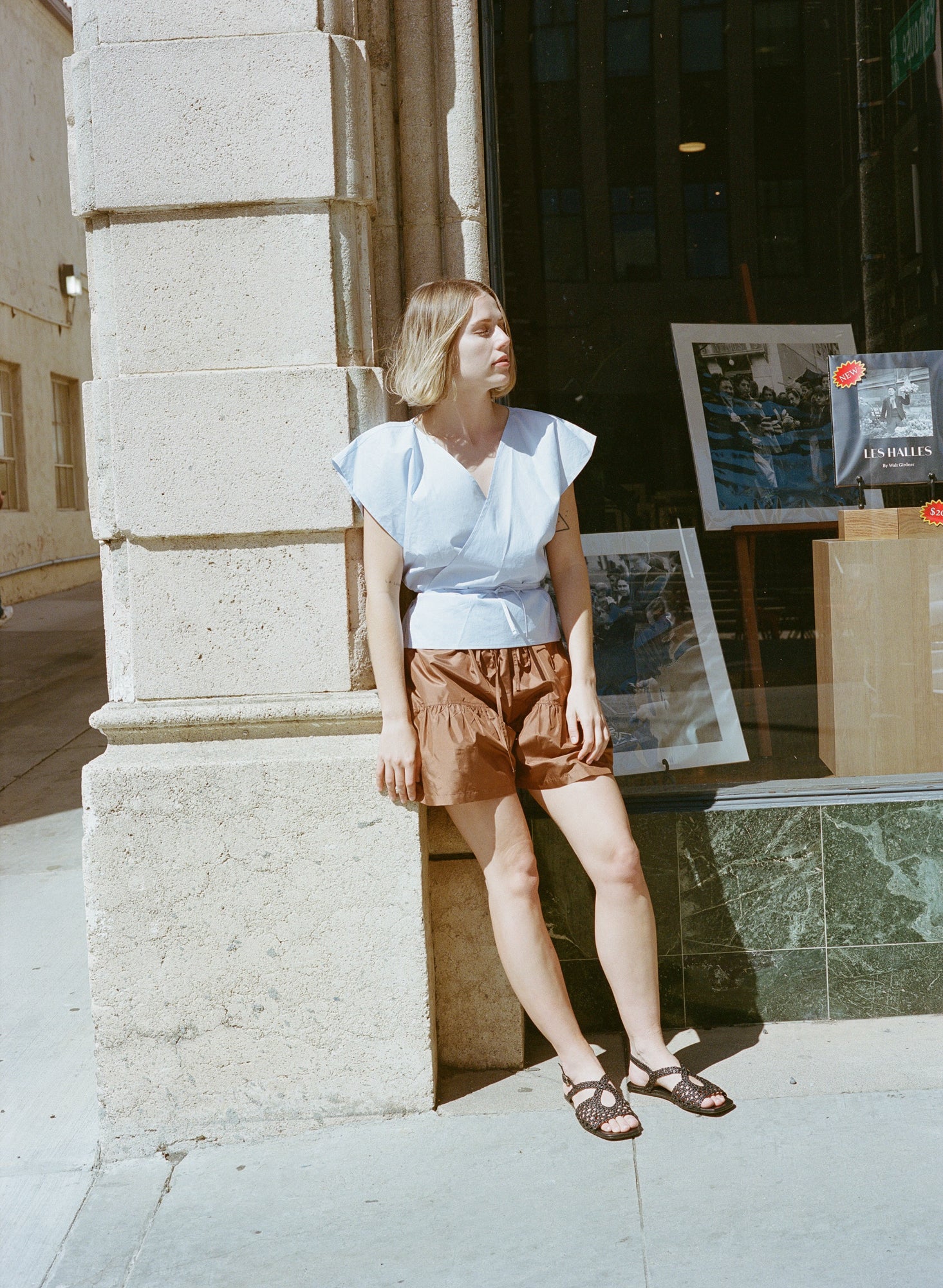 Model wears flat black leather sandals with lattice woven upper and slingback buckle.