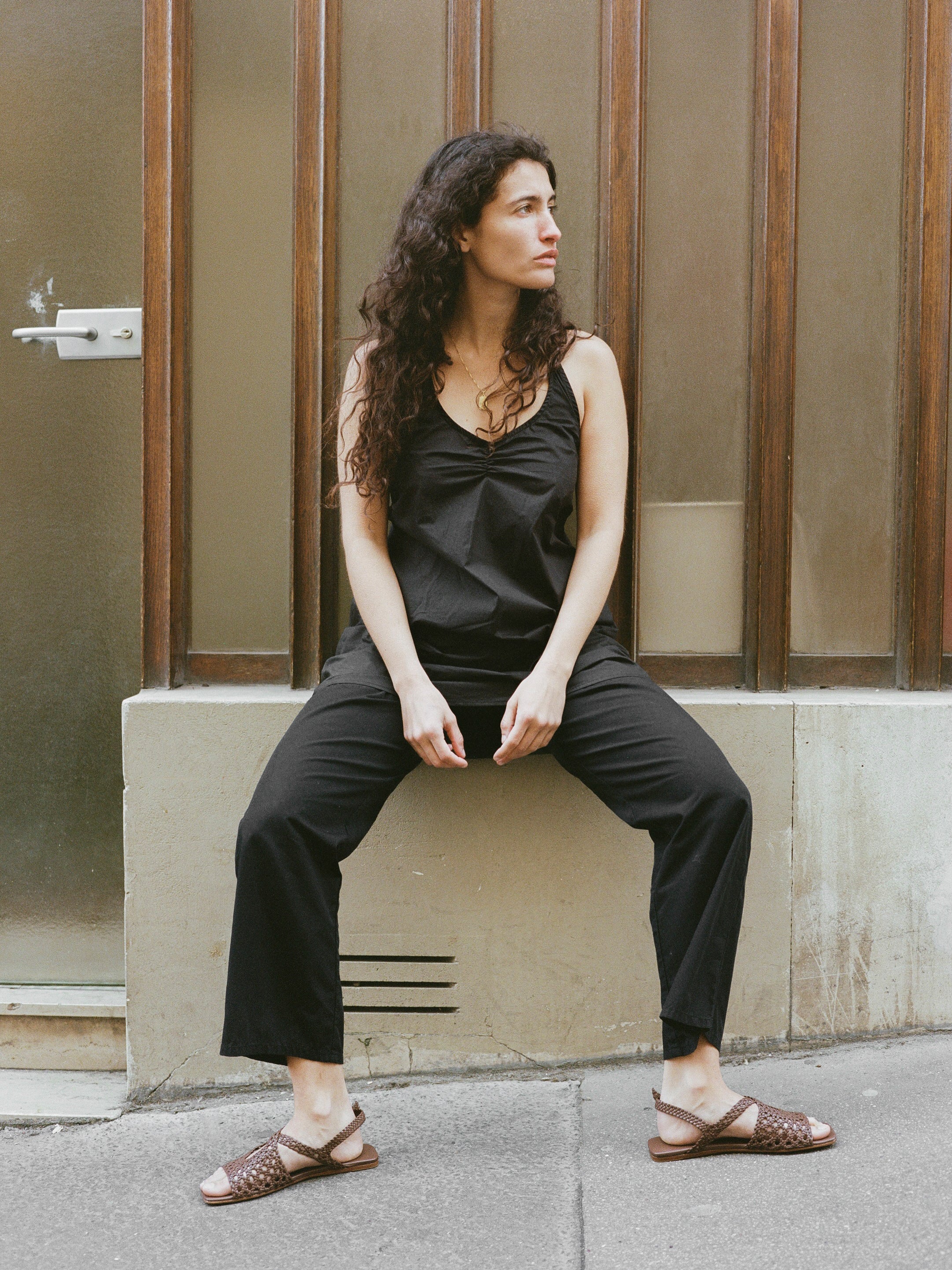 Model wears brown slingback sandals with braided upper and silver buckle clasp.