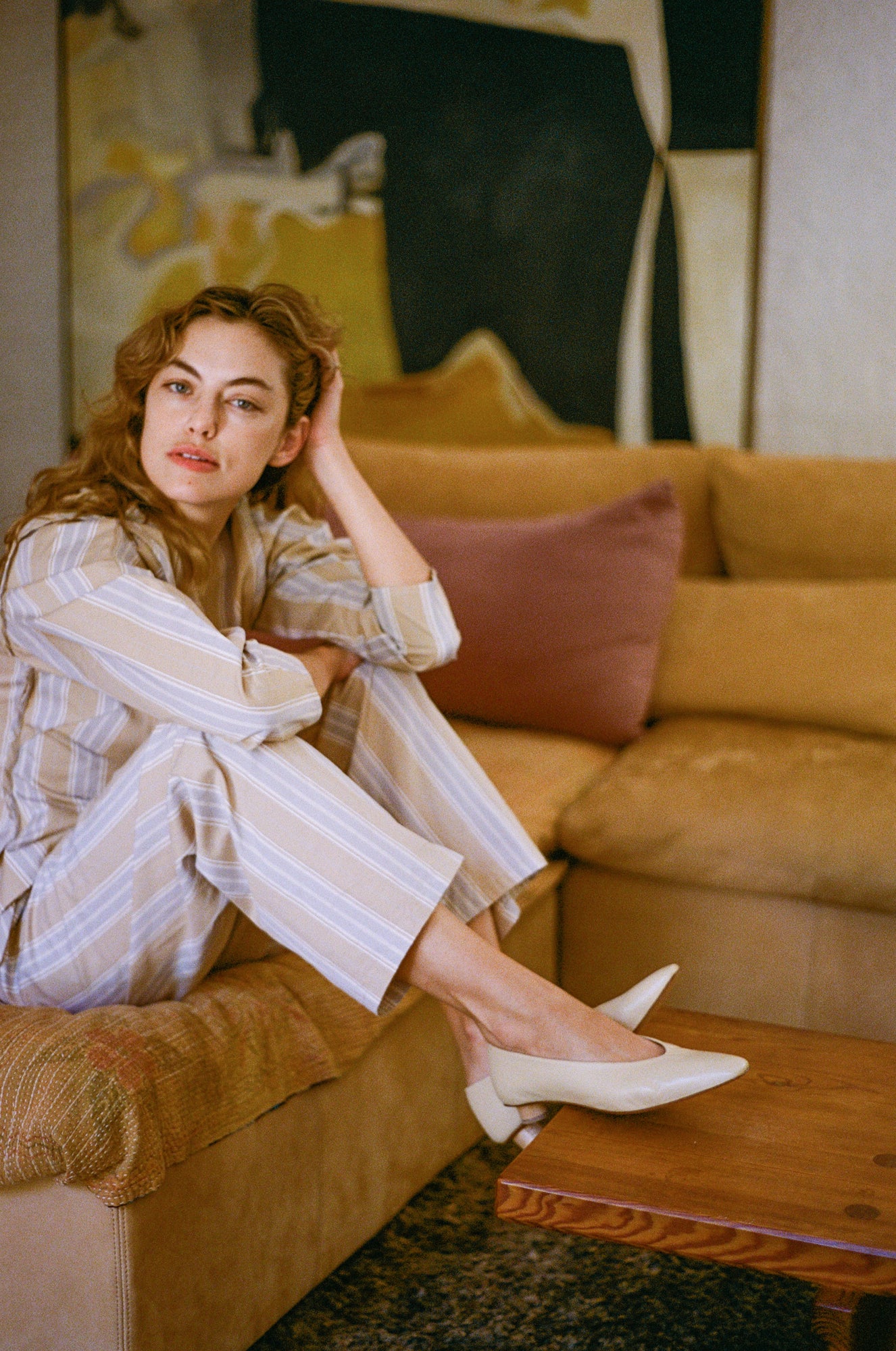 Model wears light tan colored leather ballet flat with short, cylindrical wood heel.