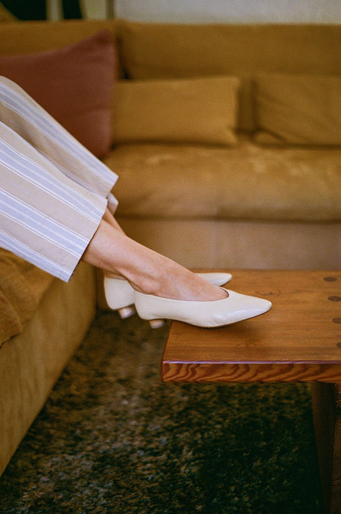 Model wears light tan colored leather ballet flat with short, cylindrical wood heel.