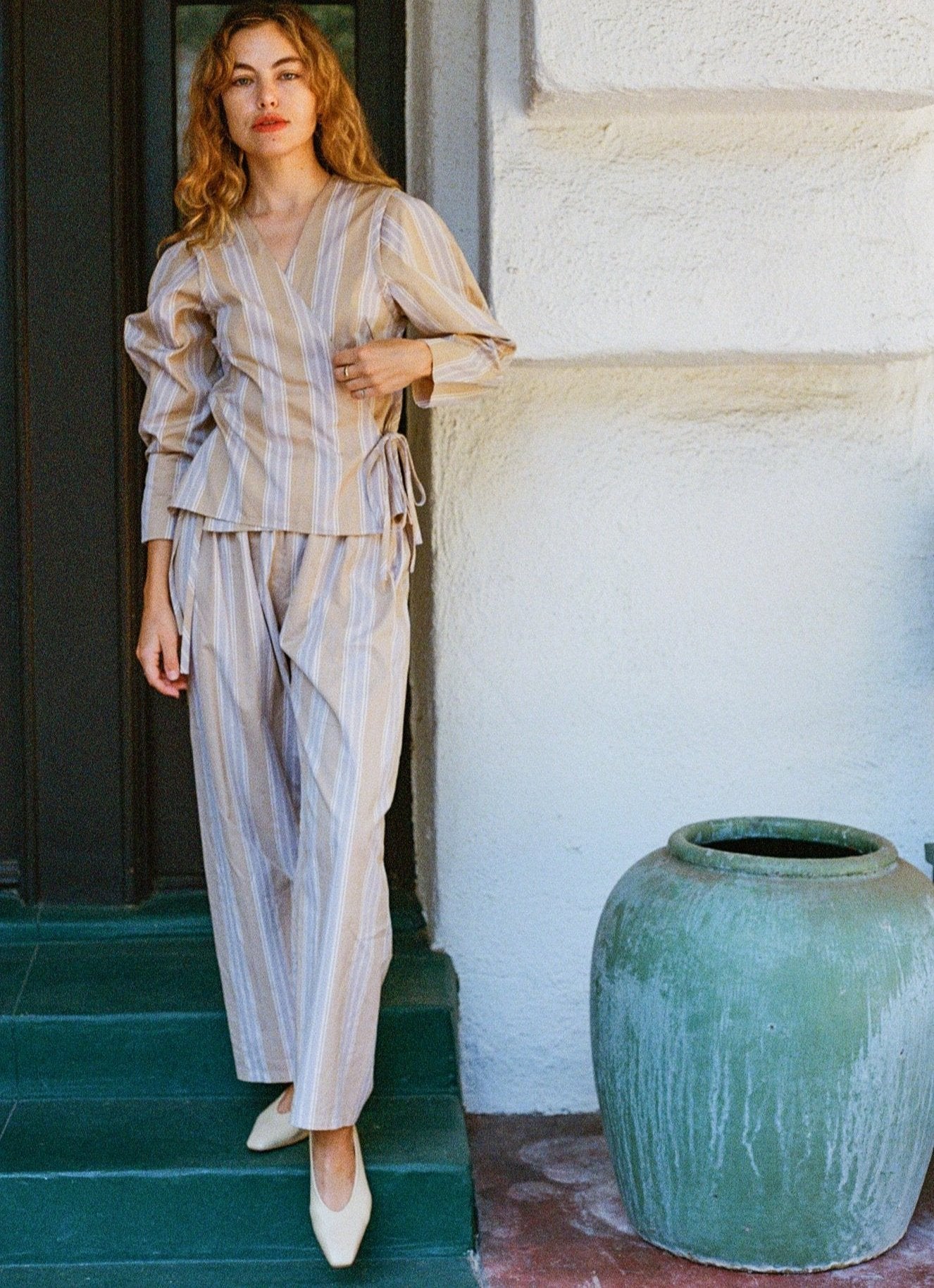 Model wears light tan colored leather ballet flat with short, cylindrical wood heel.