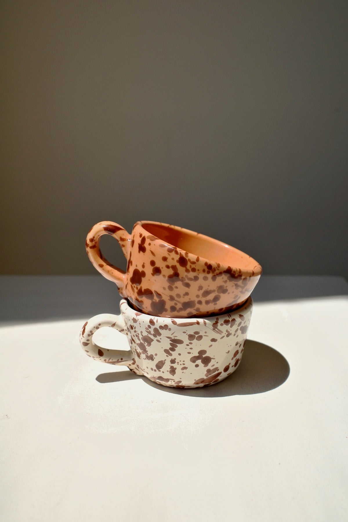 Ceramic espresso cups with white and terracotta glaze and dark brown splatter pattern.