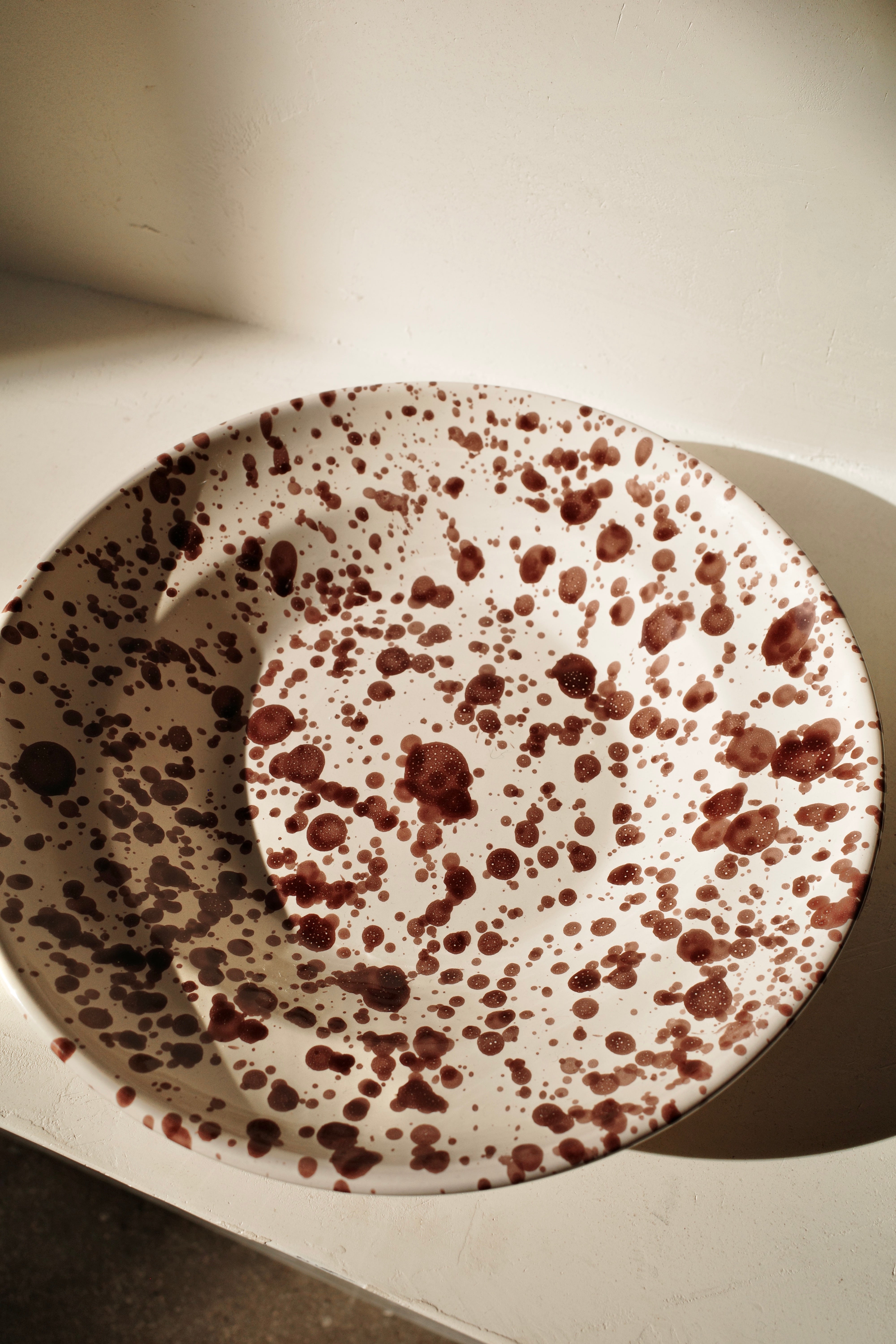 Ceramic deep plate with white glaze and dark brown paint splatter.