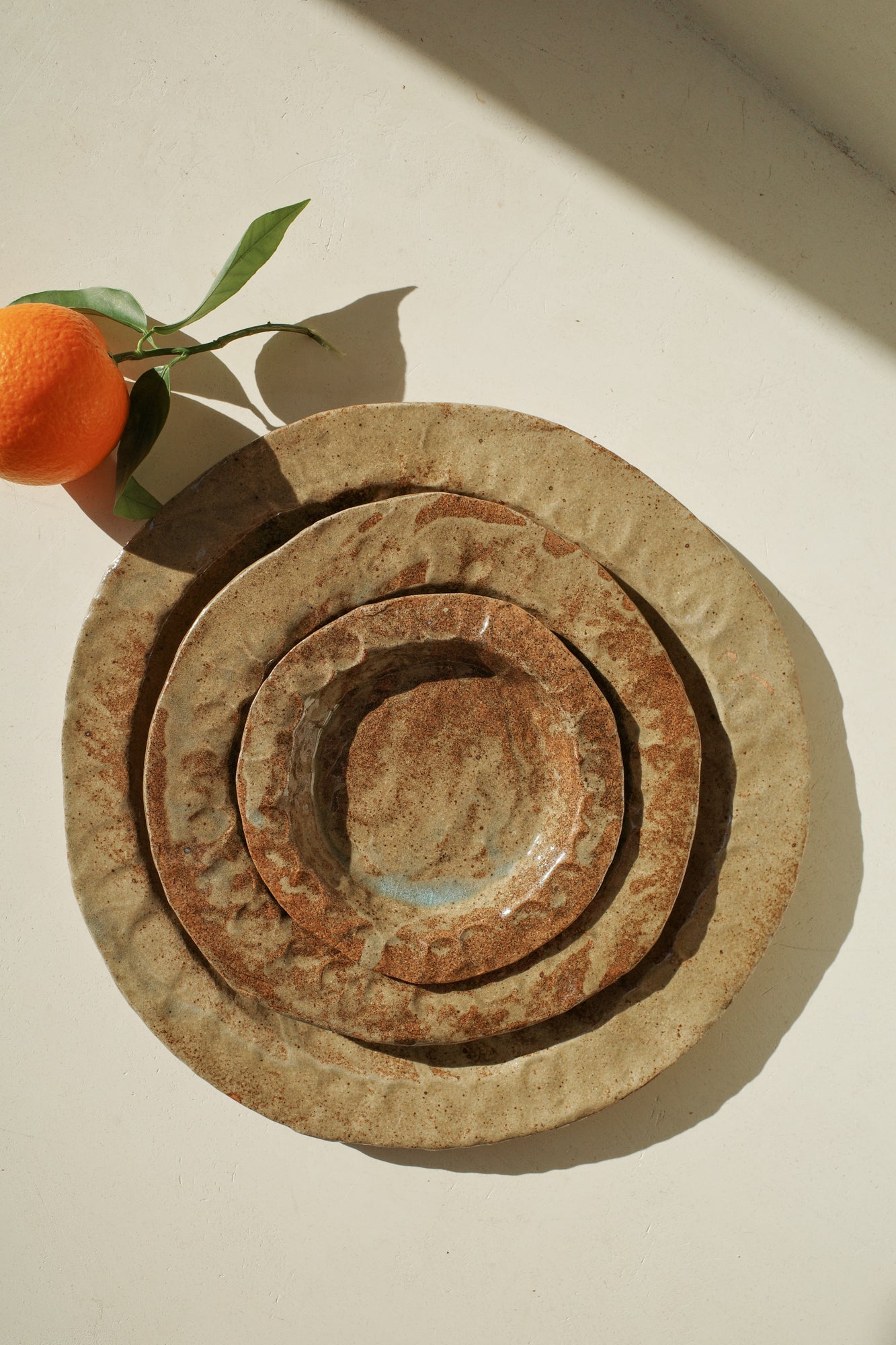 Handmade ceramic plates in varying sizes and brown glaze.