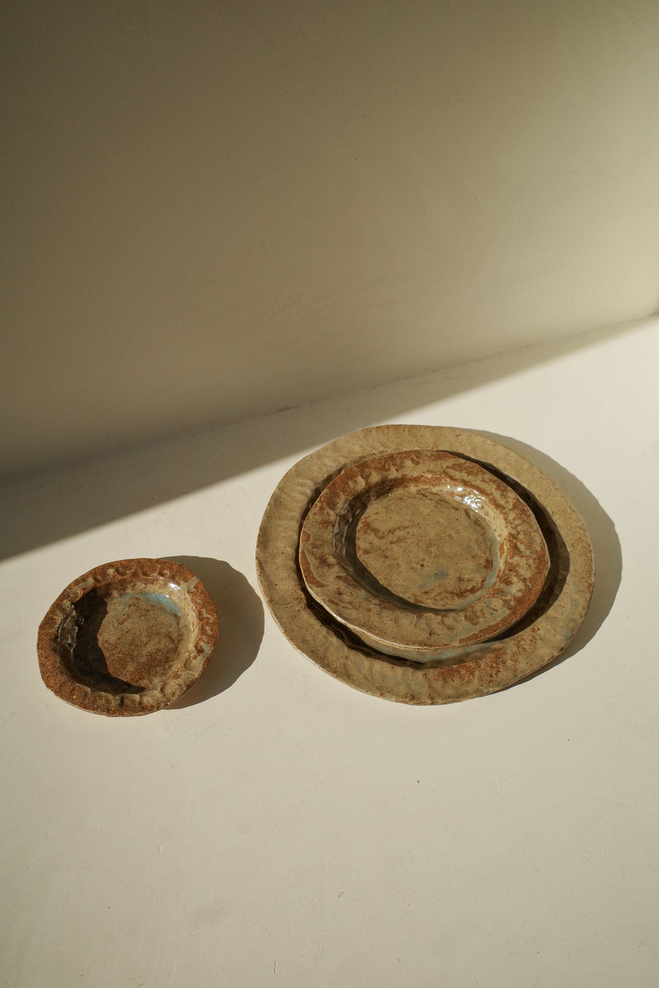 Handmade ceramic plates in varying sizes and brown glaze.