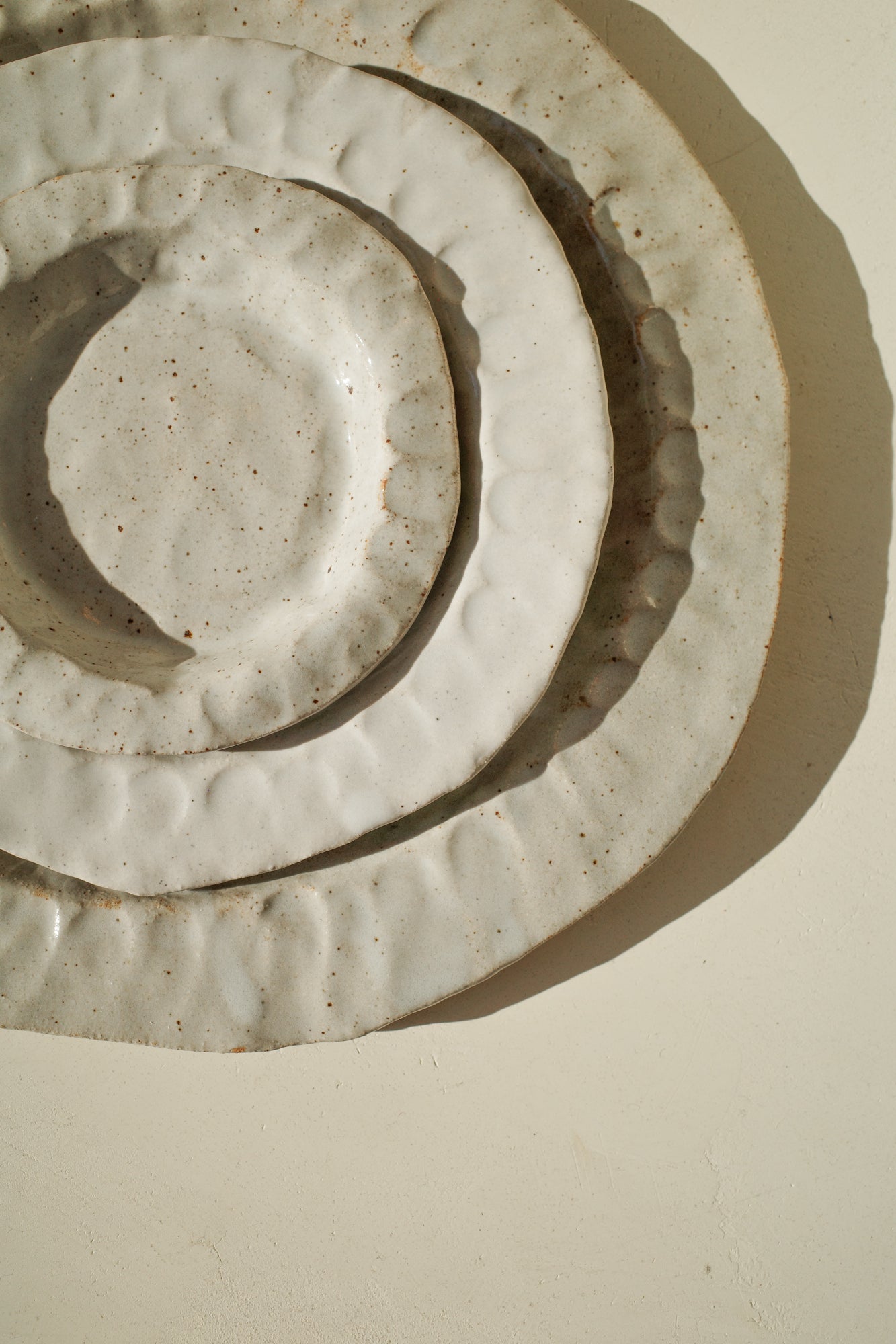 Three nesting handmade ceramic plates with white glaze.