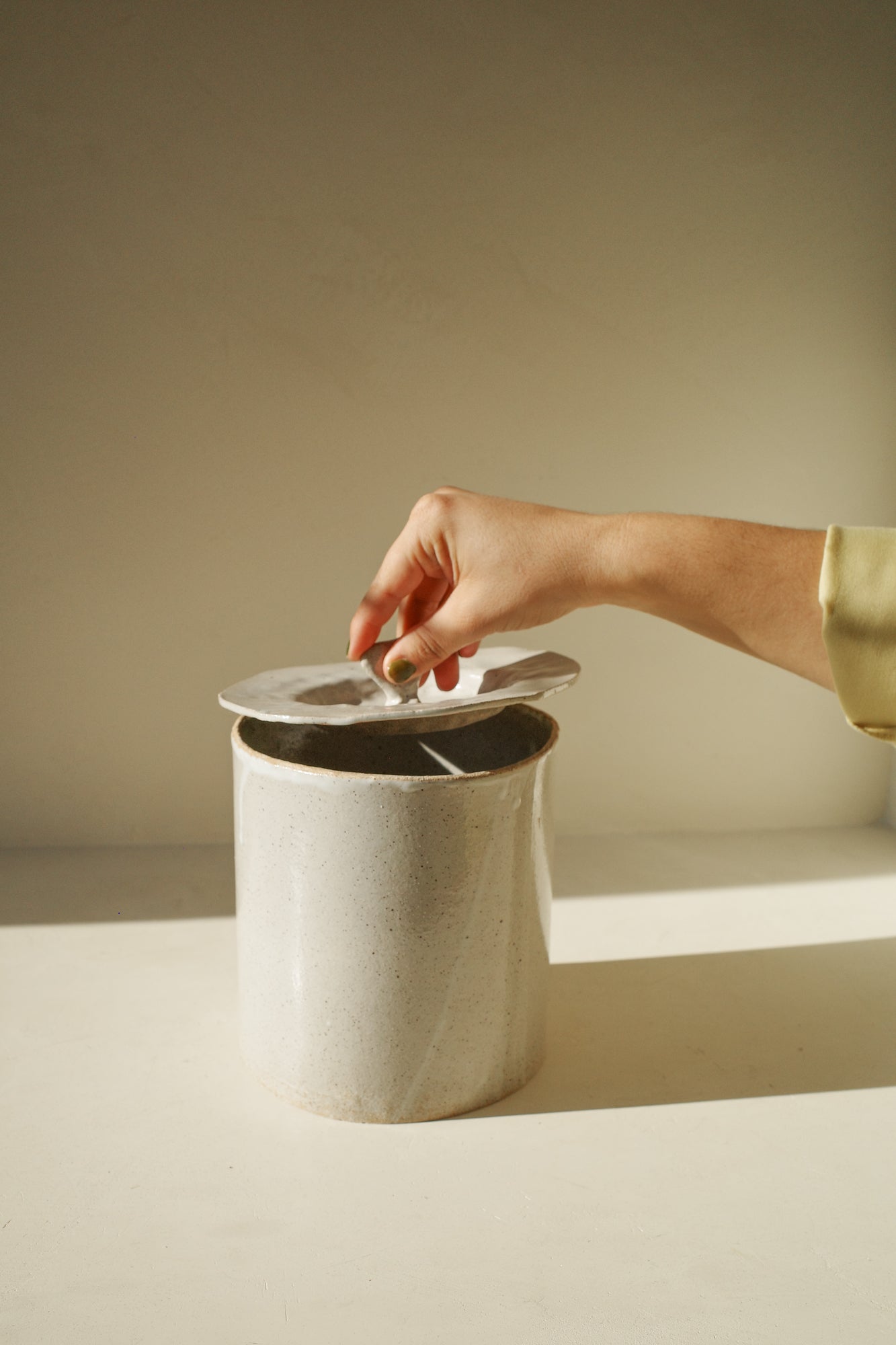 Large handbuilt ceramic jar with white glaze and removable lid.