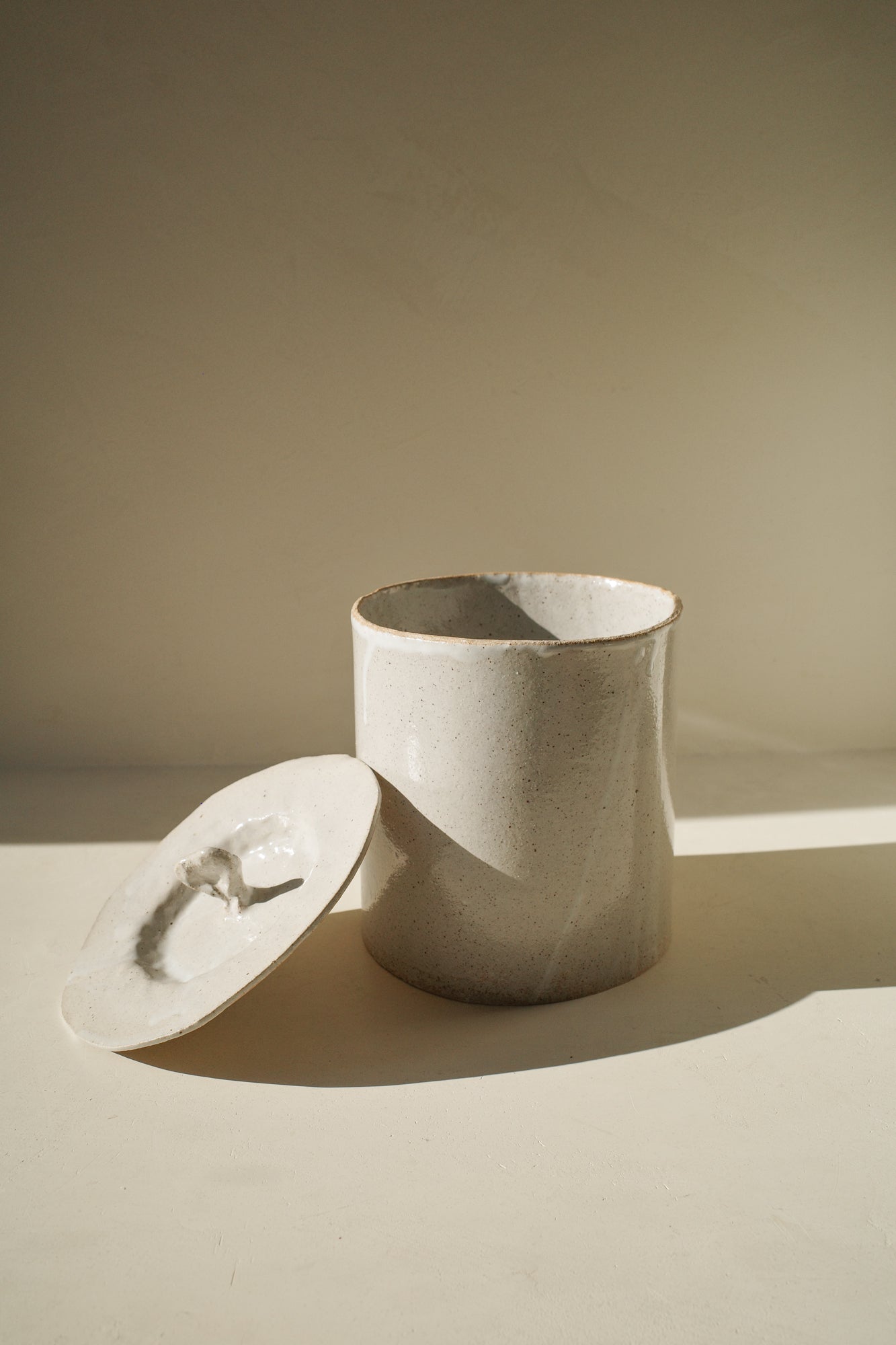 Large handbuilt ceramic jar with white glaze and removable lid.