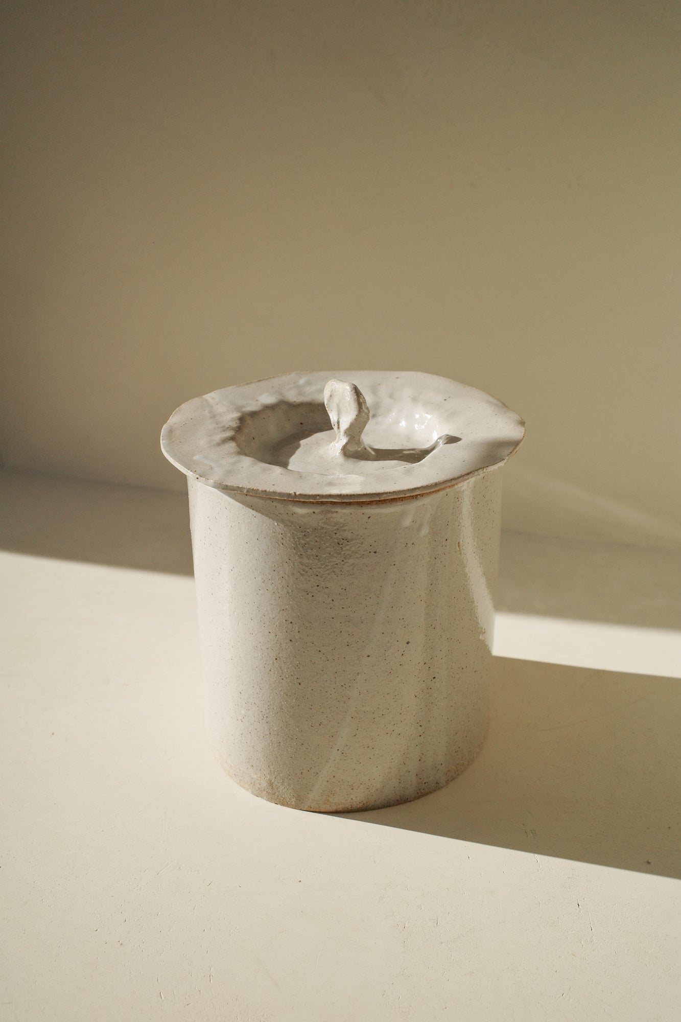 Large handbuilt ceramic jar with white glaze and removable lid.
