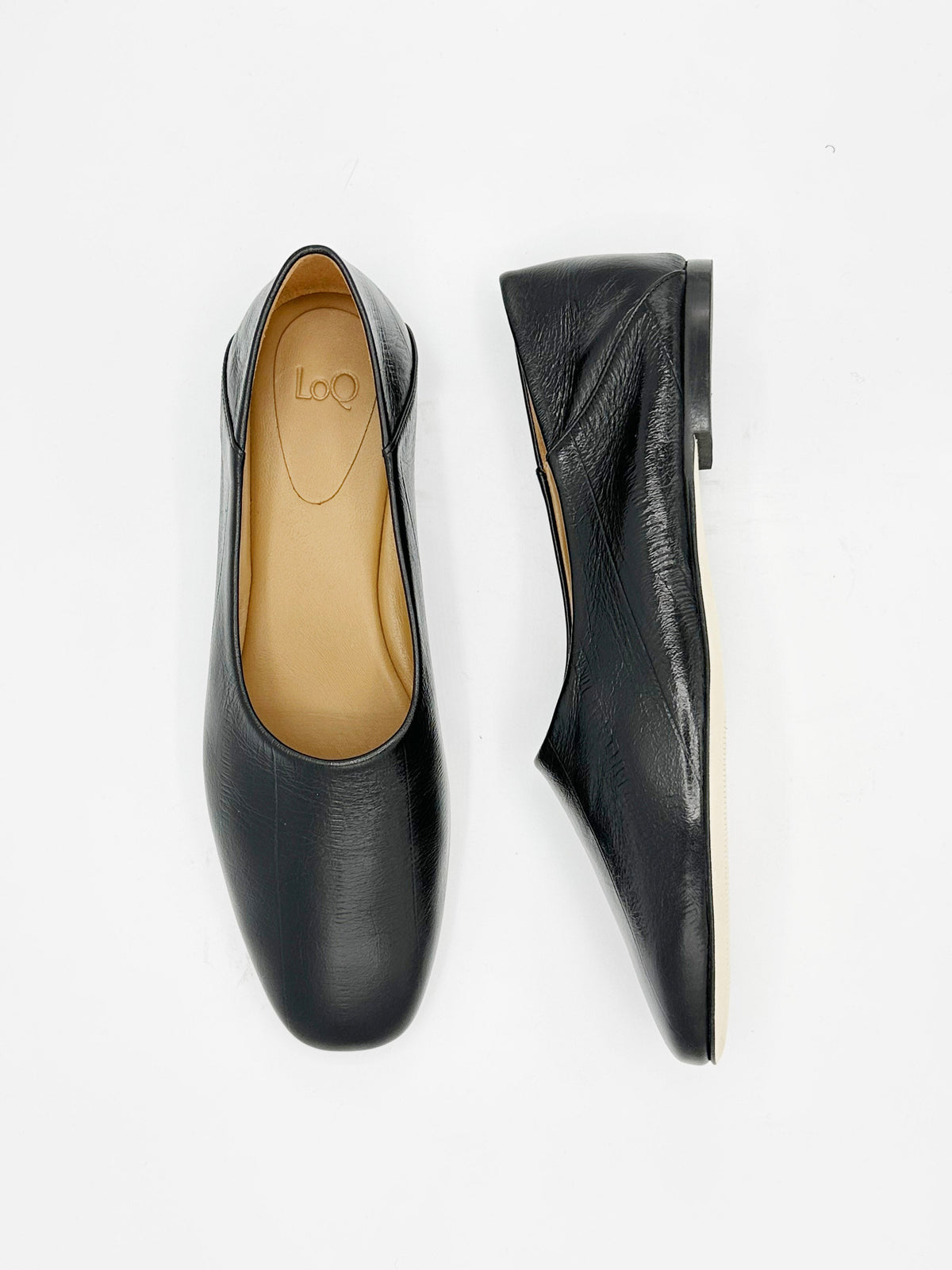 A pair of black eel embossed leather flats with square toe, and collapsible back.
