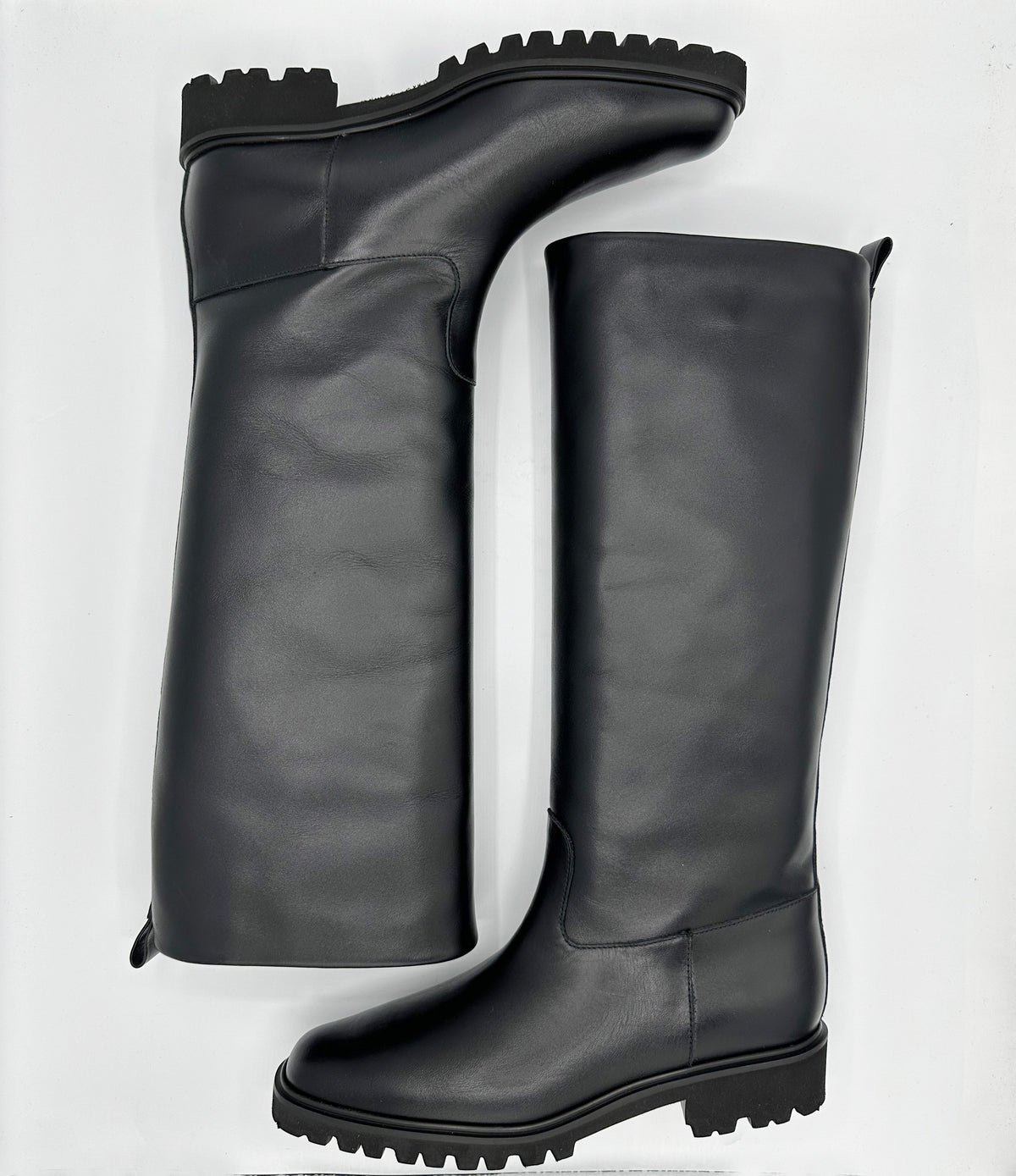A pair of black leather knee-high boots with rugged lug soles.