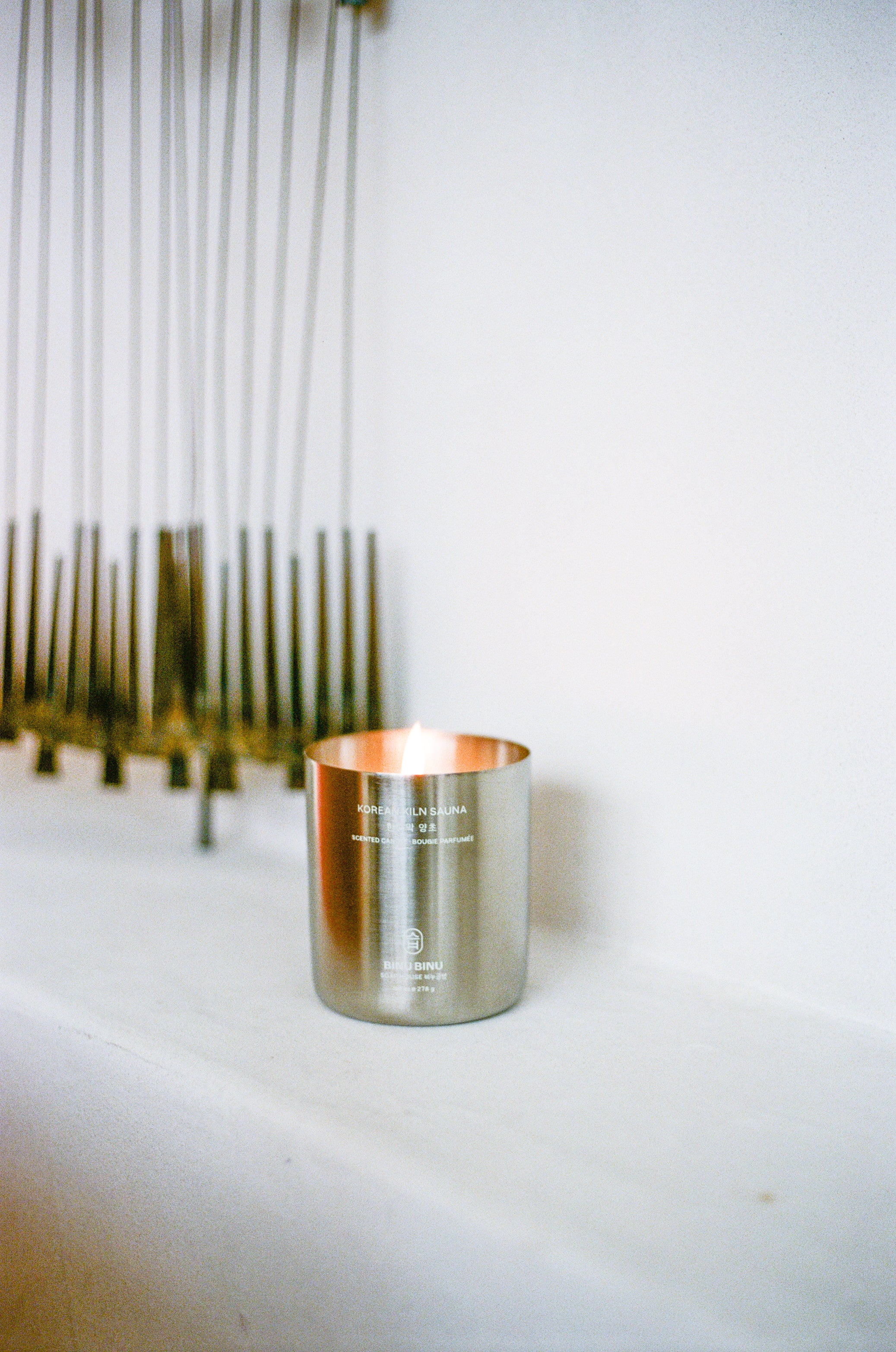 Candle in metal container on surface.