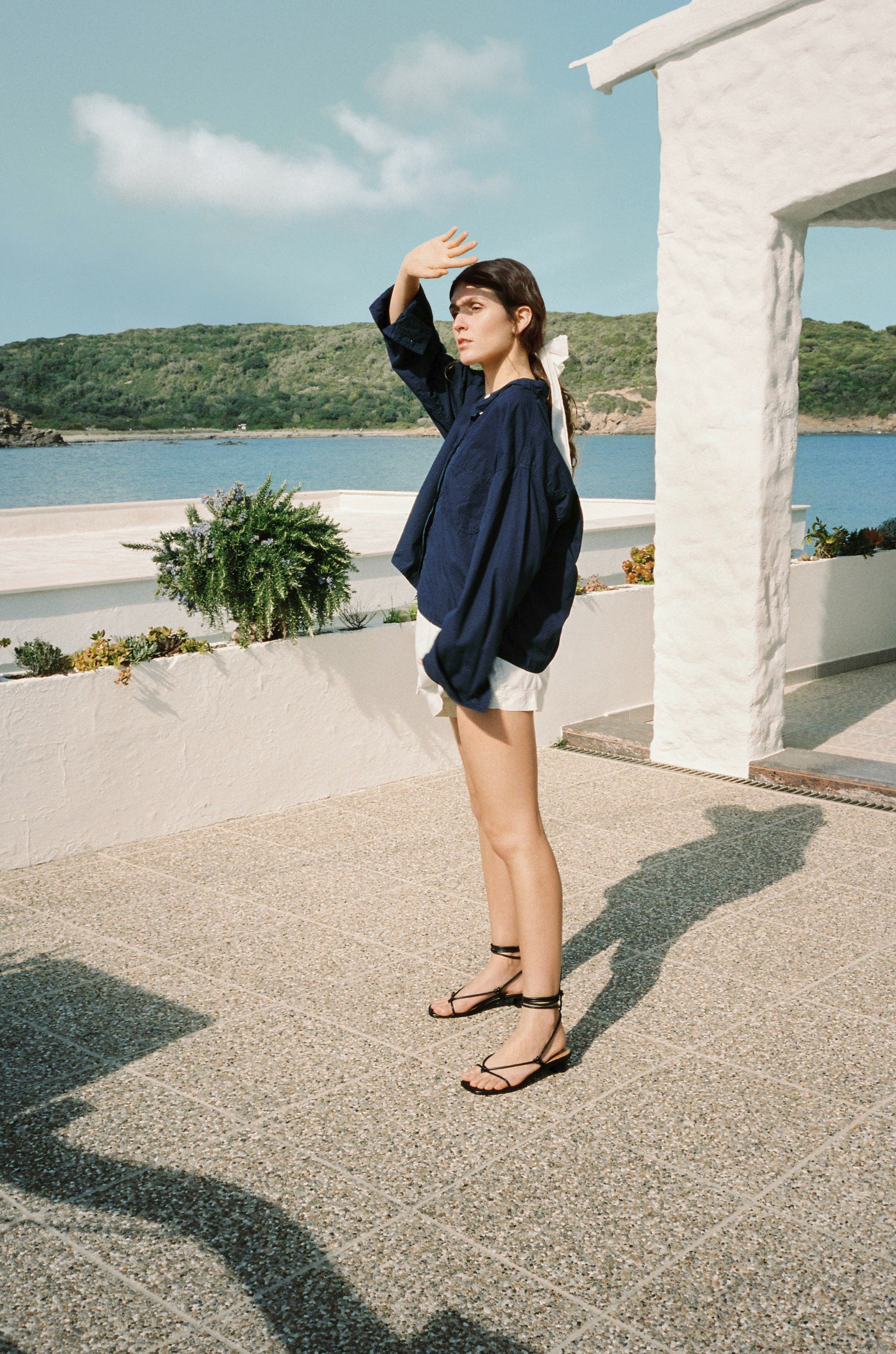 Knotted thong sandal featuring a short heel and tubular black leather straps that wrap around the ankle to tie.