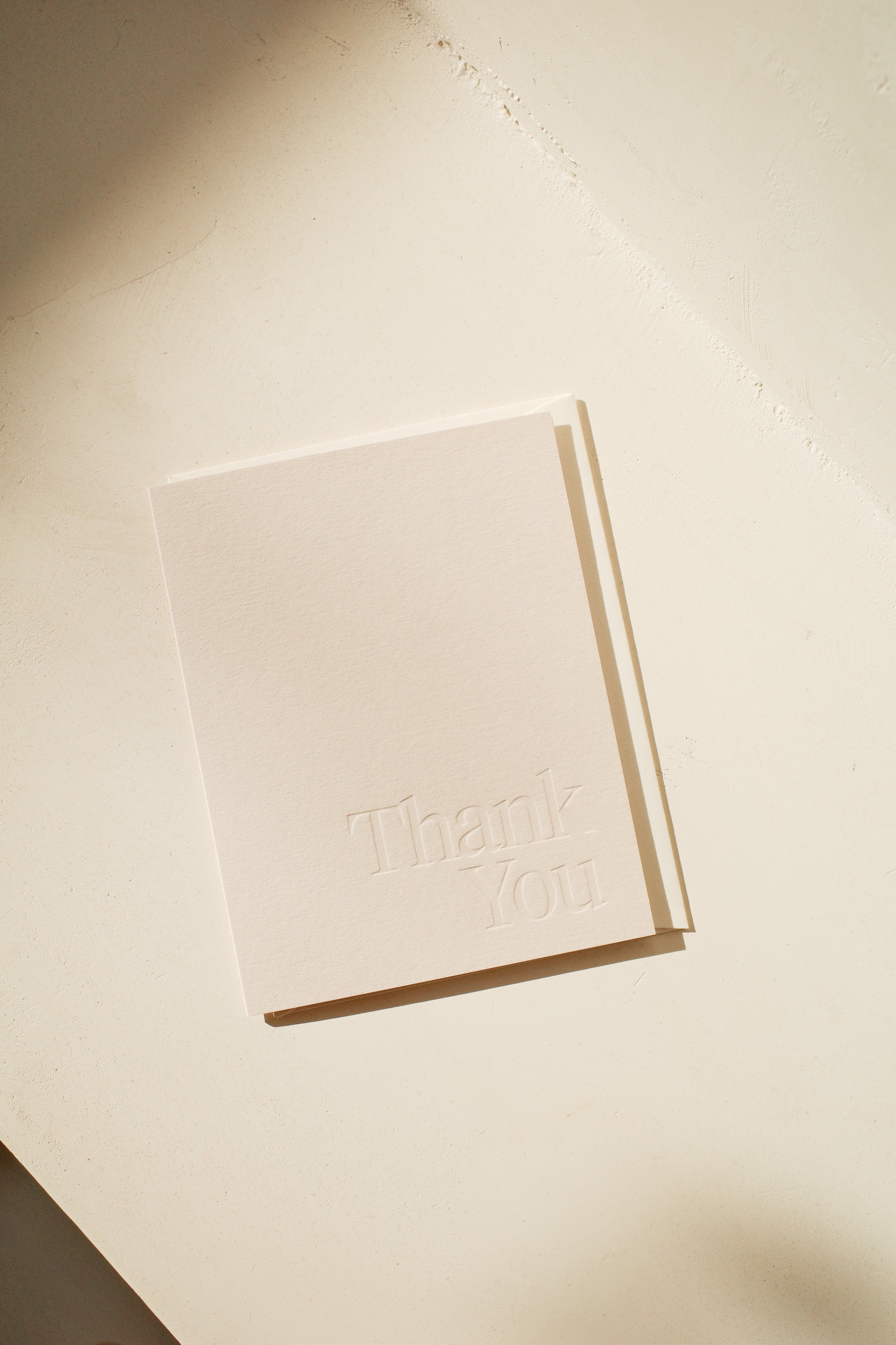 White greeting card with Thank You embossed on front.