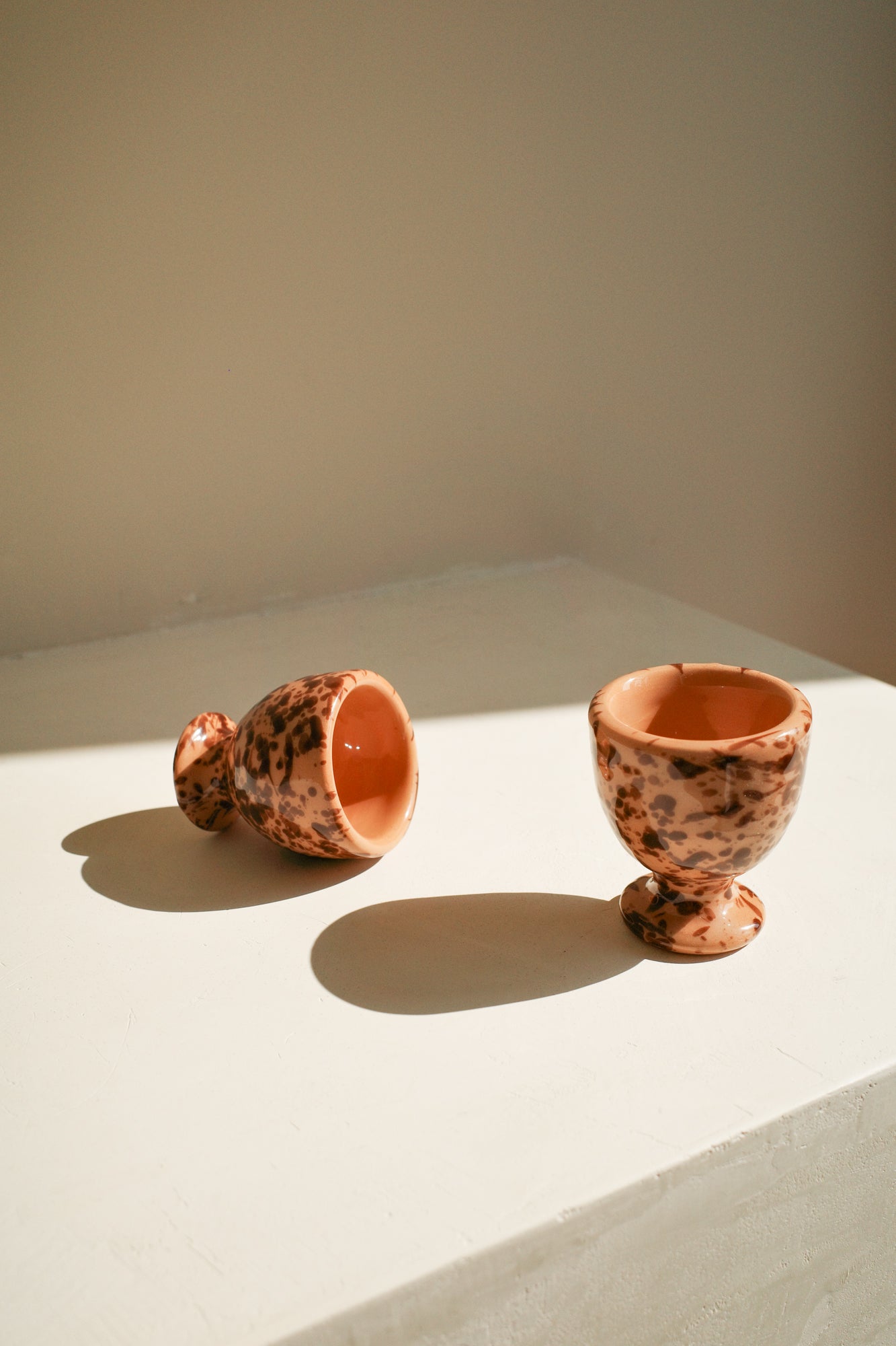 Ceramic egg cups with terracotta glaze and brown splatter pattern.
