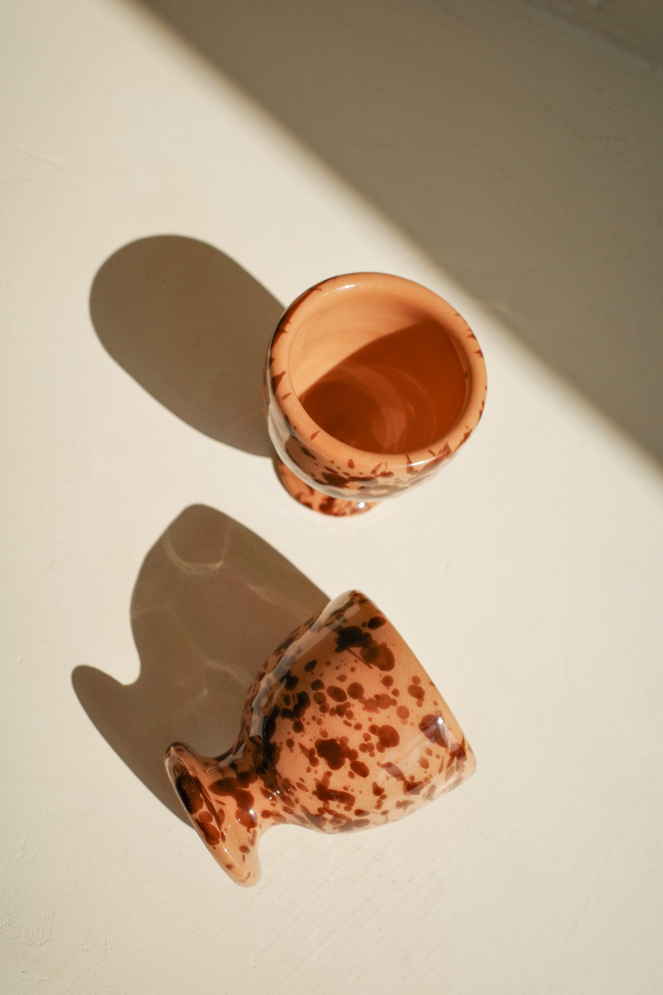 Ceramic egg cups with terracotta glaze and brown splatter pattern.