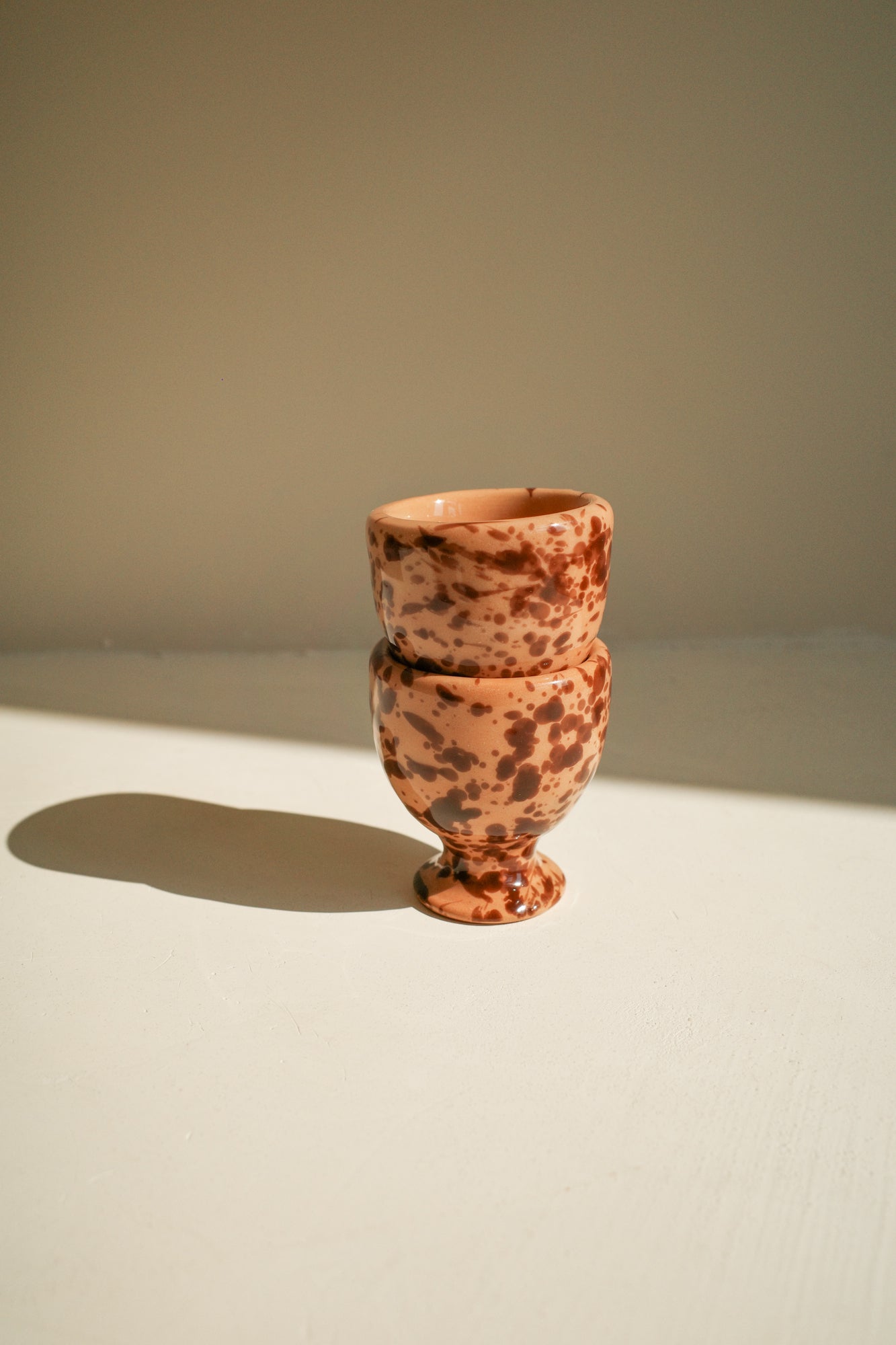 Ceramic egg cups with terracotta glaze and brown splatter pattern.