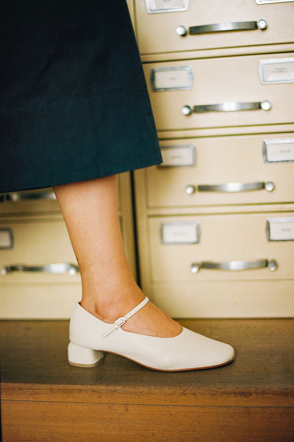 Modern Mary Jane featuring a classic silver buckle with an updated round heel in an off white color leather. Round toe and 1" covered heel.