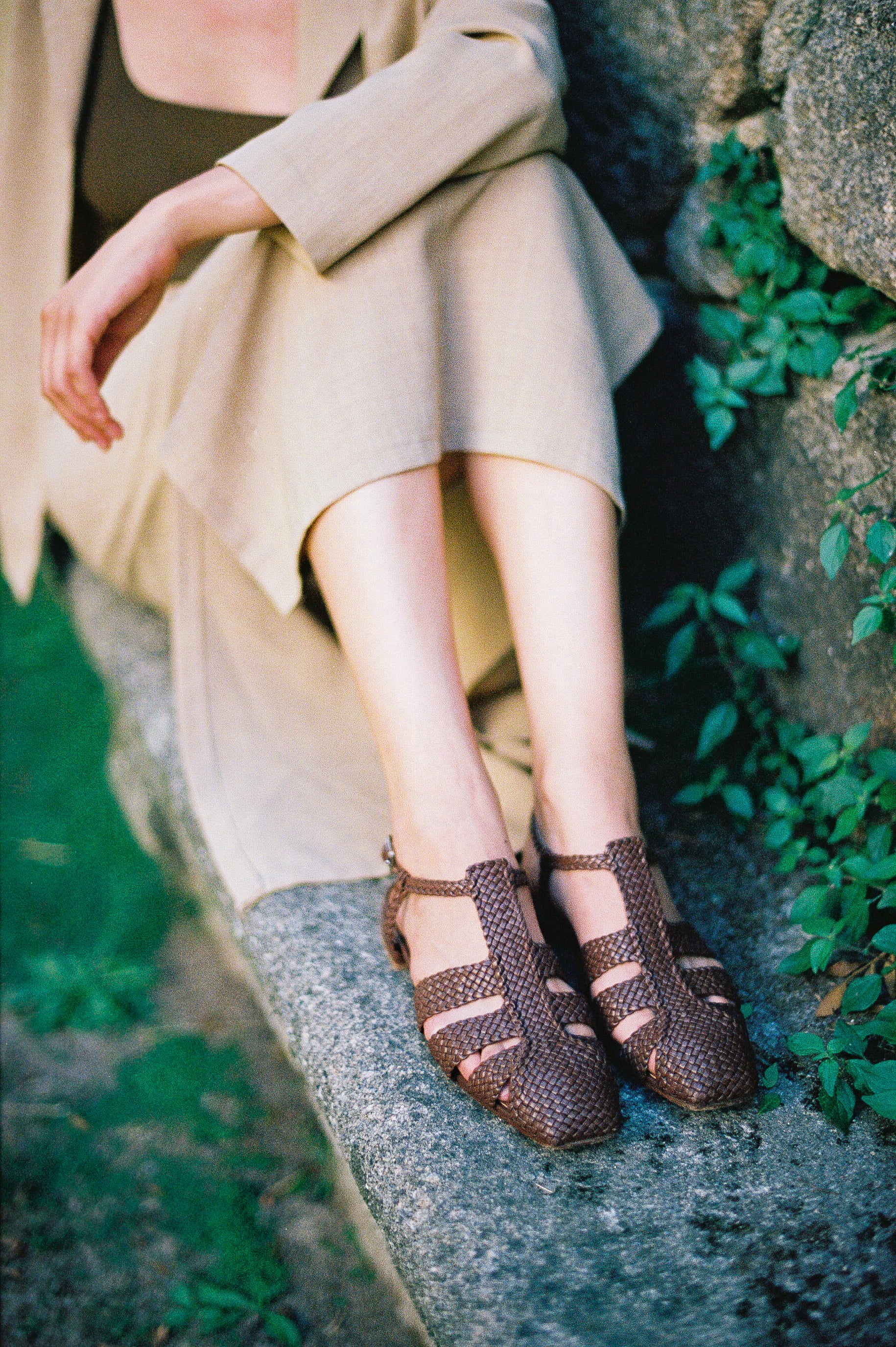 Brown leather fisherman-style sandals featuring straps made of woven leather across the foot and a strap that buckles around the ankle