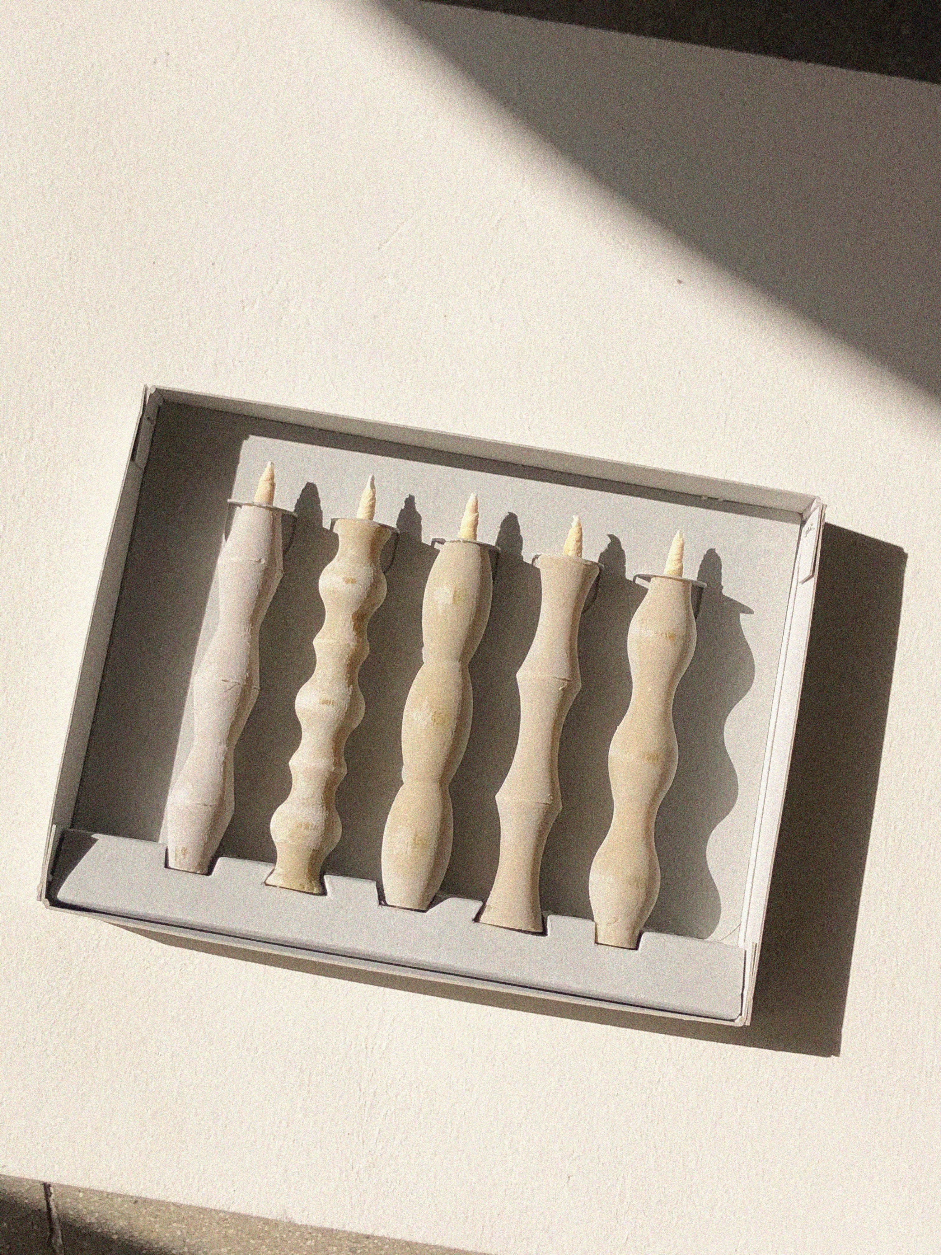 Set of five off-white candles, each one with a different wavy silhouette.