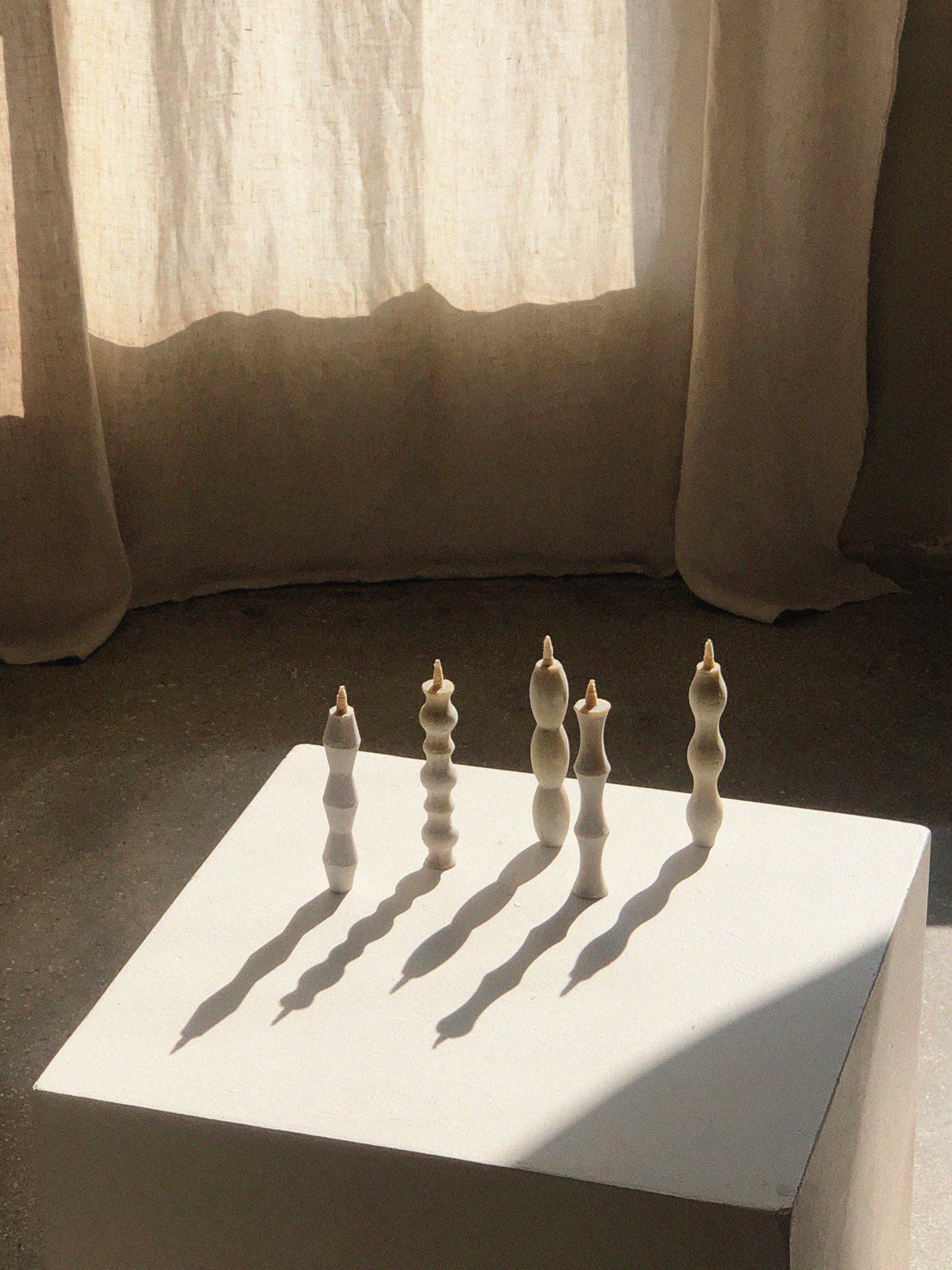 Set of five off-white candles, each one with a different wavy silhouette.