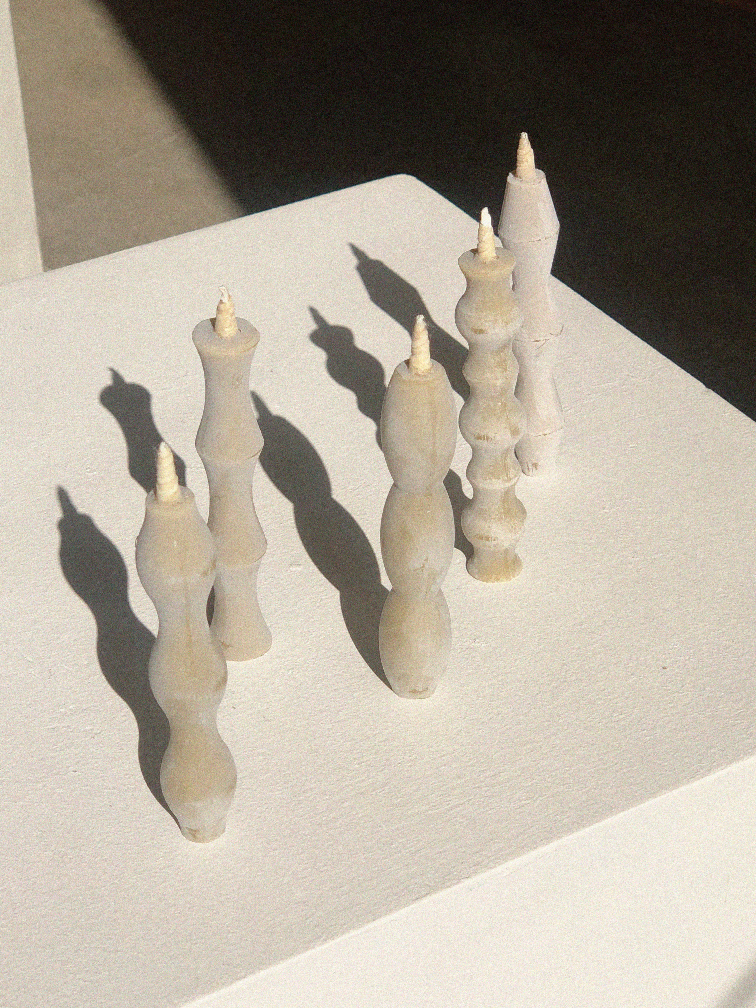 Set of five off-white candles, each one with a different wavy silhouette.